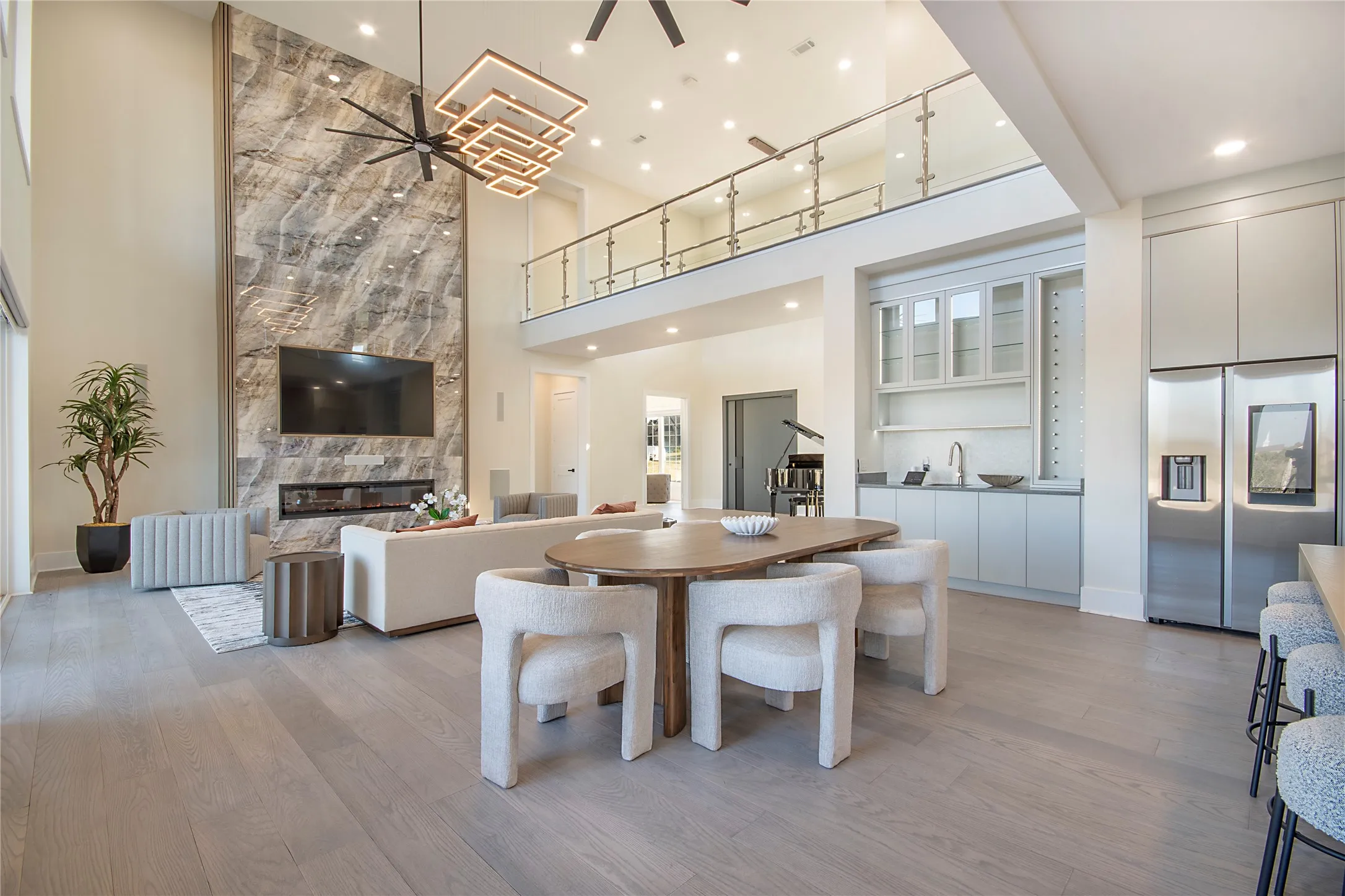 Dining space featuring ceiling fan, light wood-style flooring, a fireplace, and a high ceiling