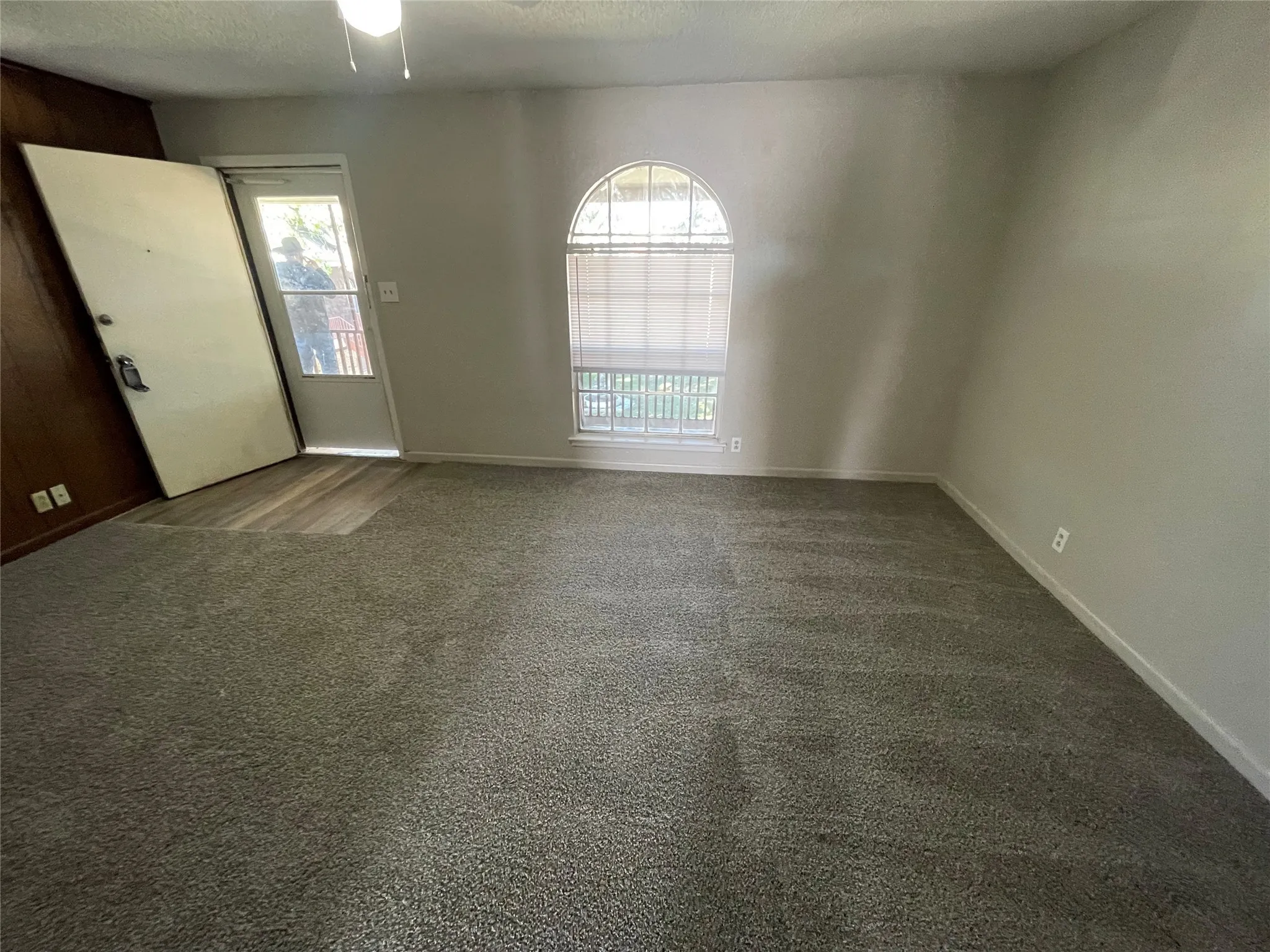 Unfurnished room with dark colored carpet and a textured ceiling