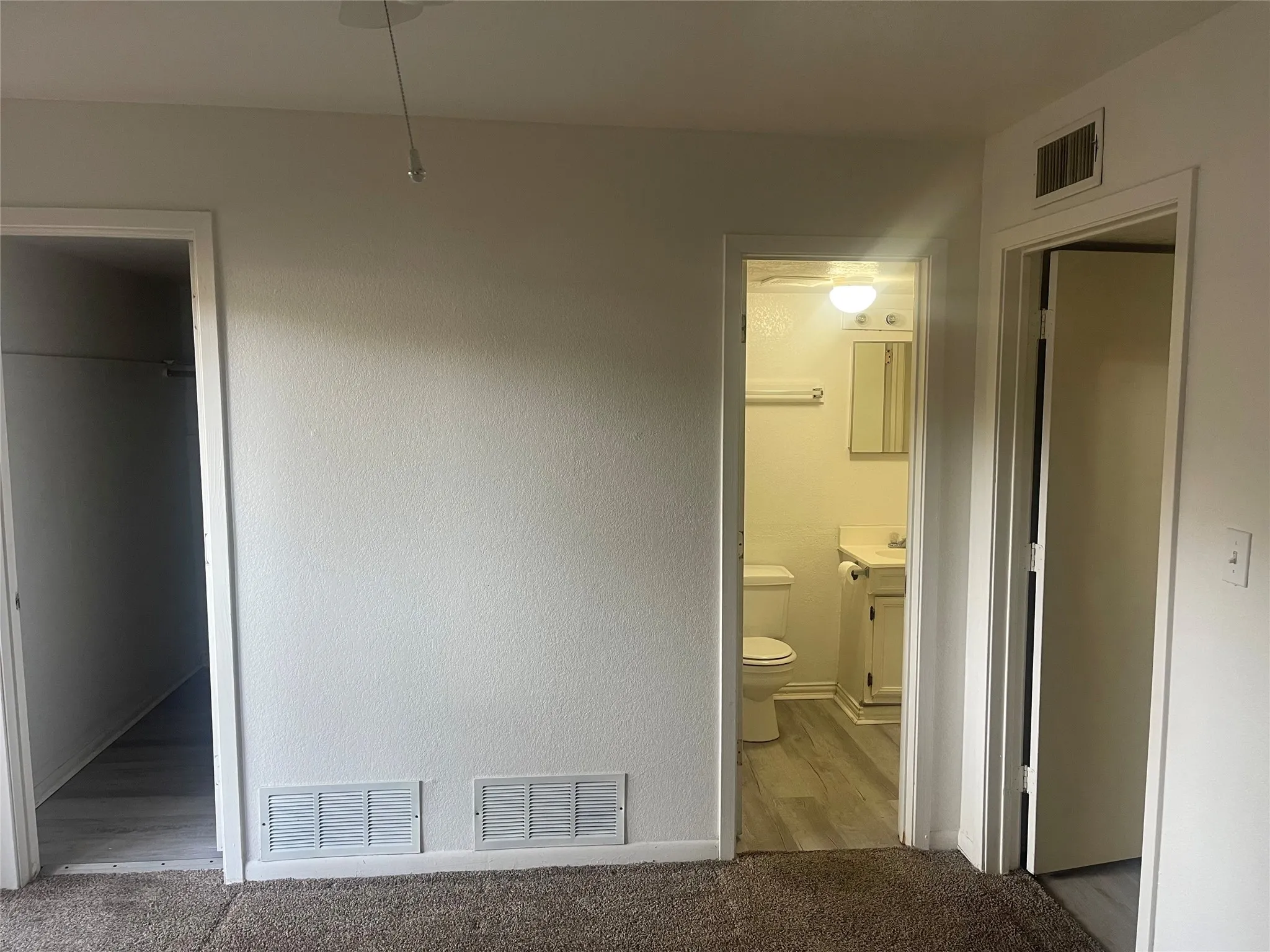 Unfurnished bedroom with ensuite bath and carpet flooring