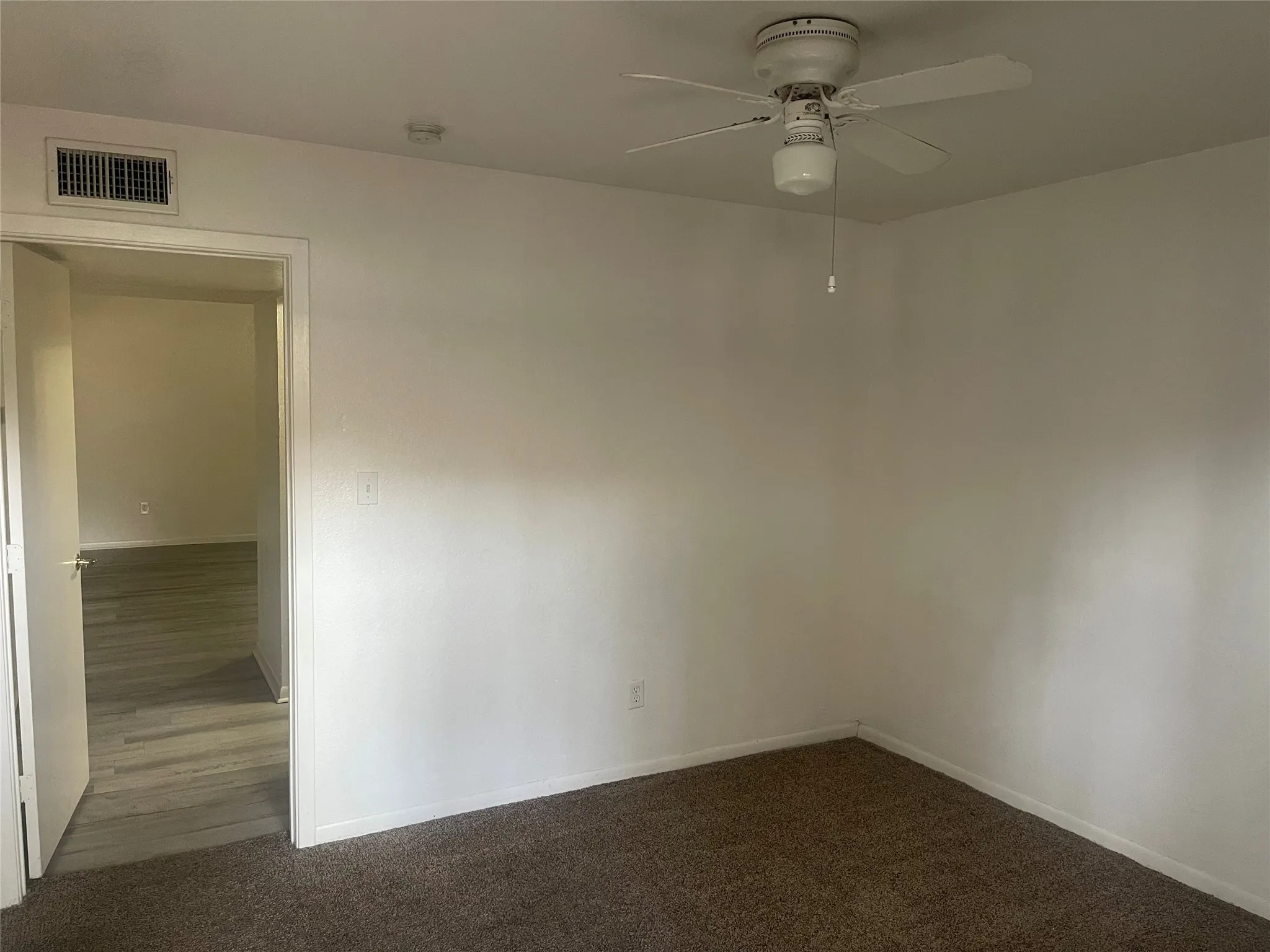 Unfurnished room featuring ceiling fan and dark carpet