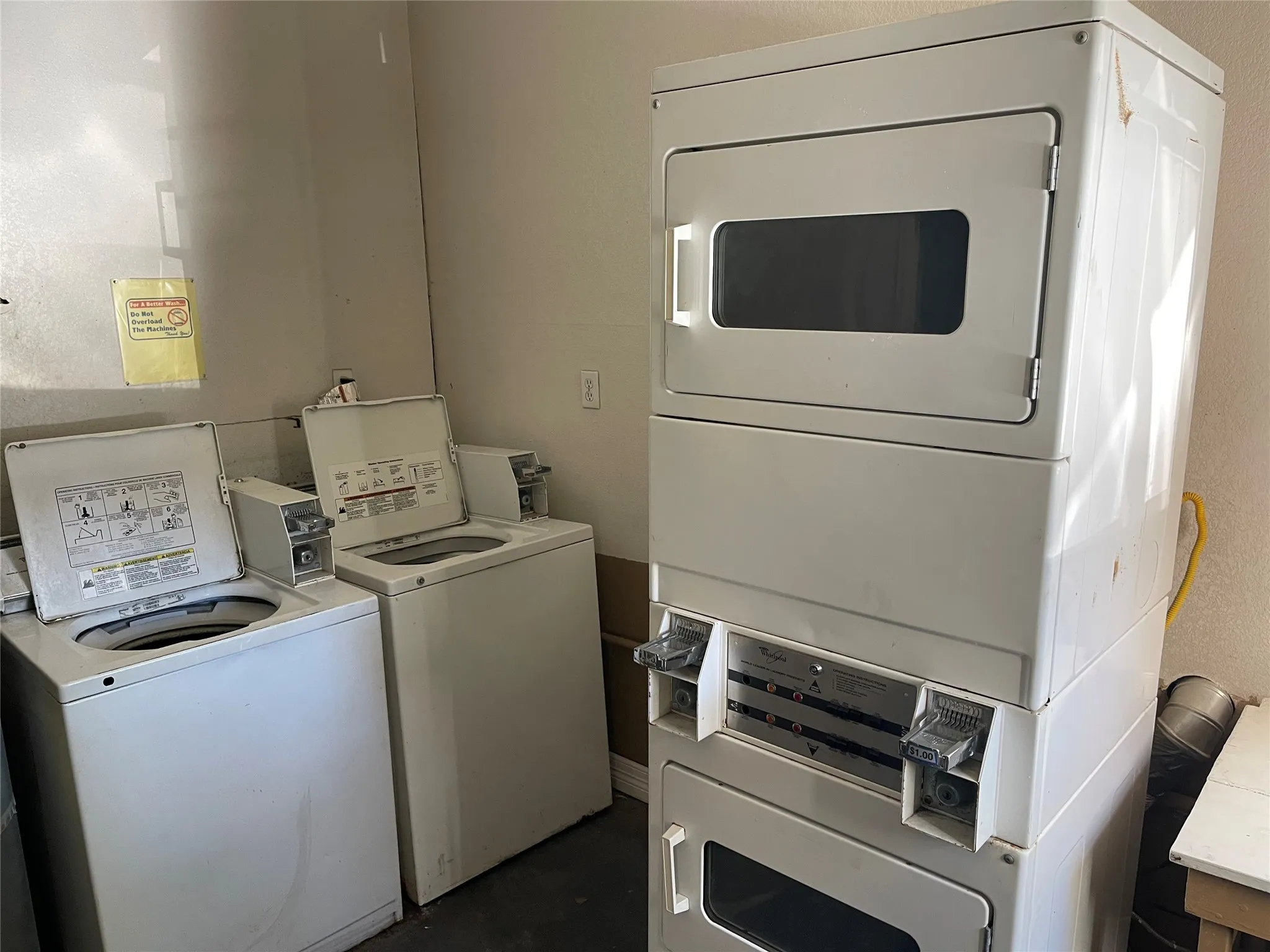Communal laundry room with stacked washer and clothes dryer