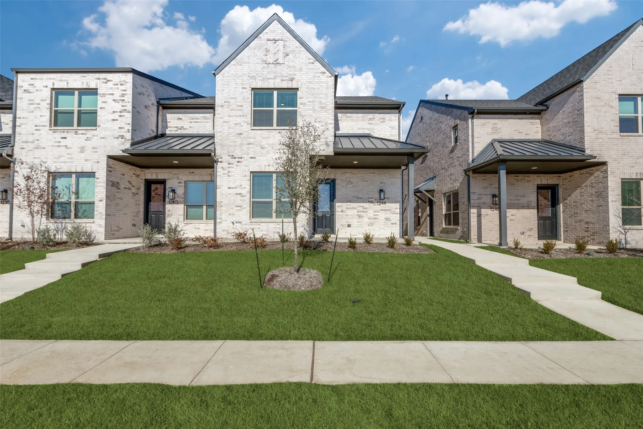 View of front of property with a standing seam roof, brick siding, and a metal roof