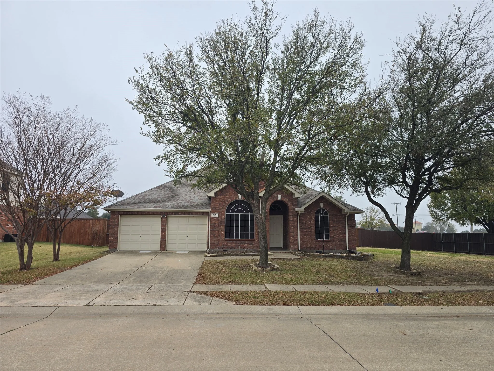 View of front of property with concrete driveway, brick siding, a garage, and roof with shingles