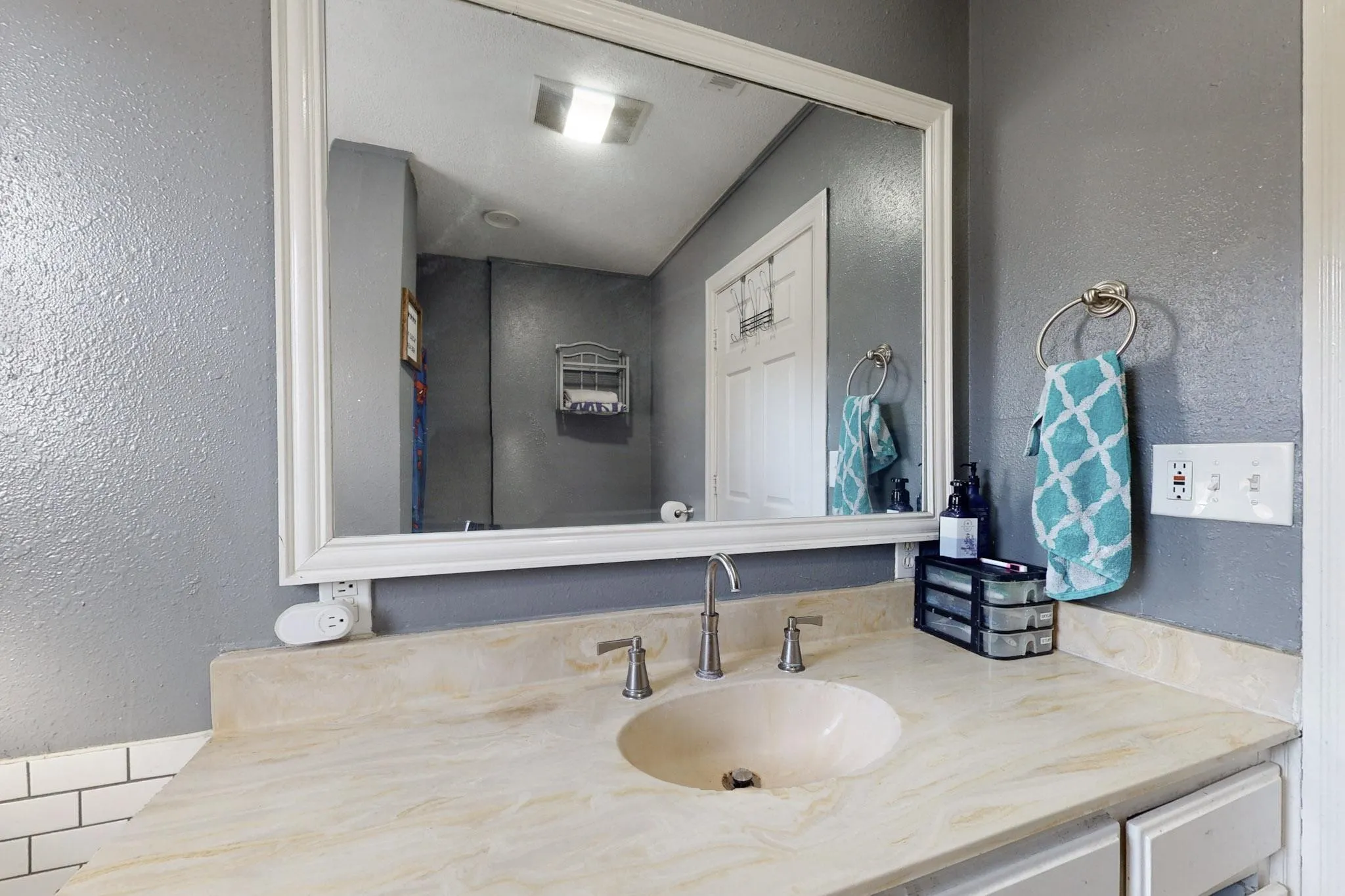 Bathroom featuring a textured wall and vanity