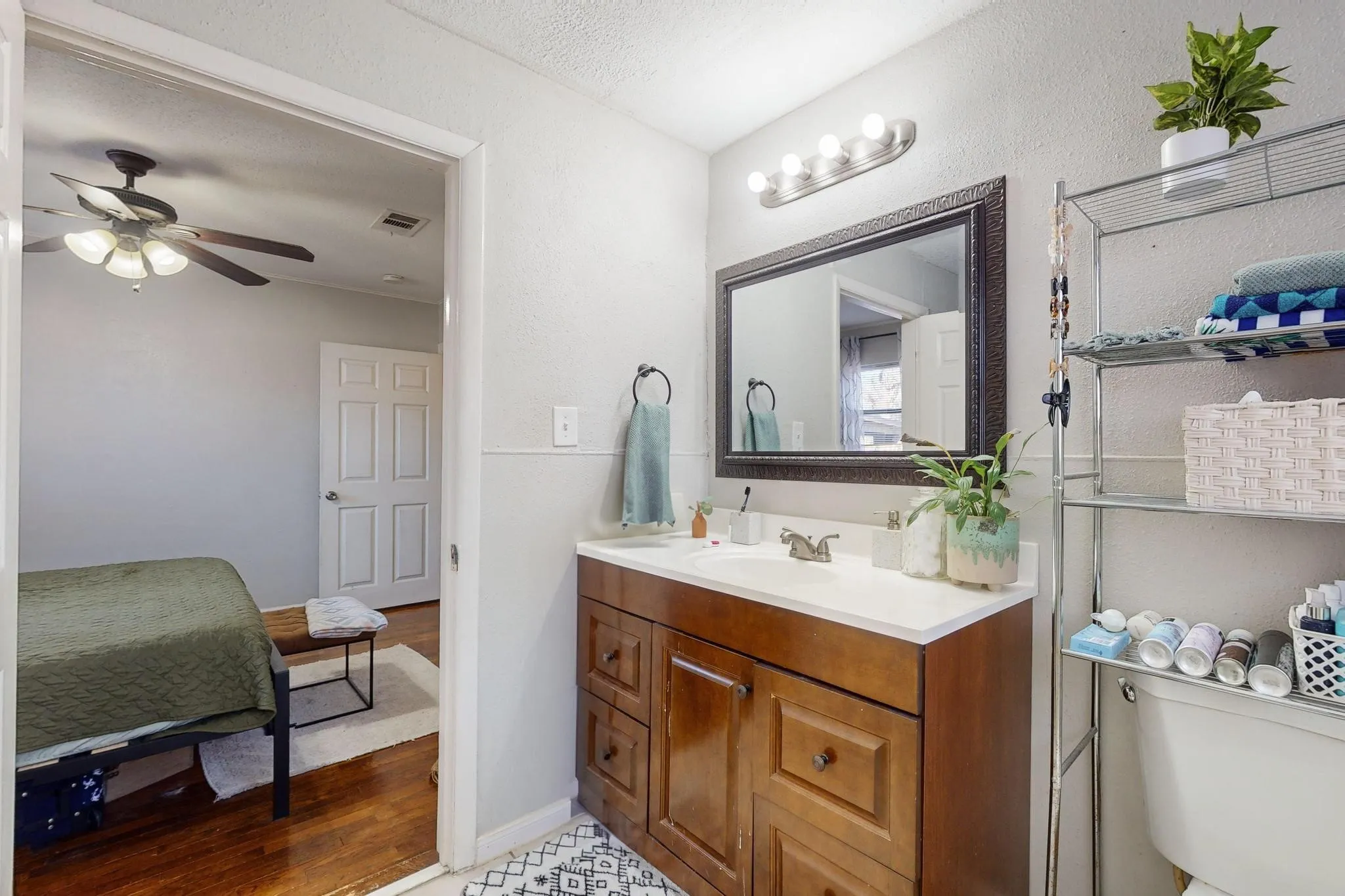 Bathroom featuring vanity, connected bathroom, light wood finished floors, a textured ceiling, and ceiling fan
