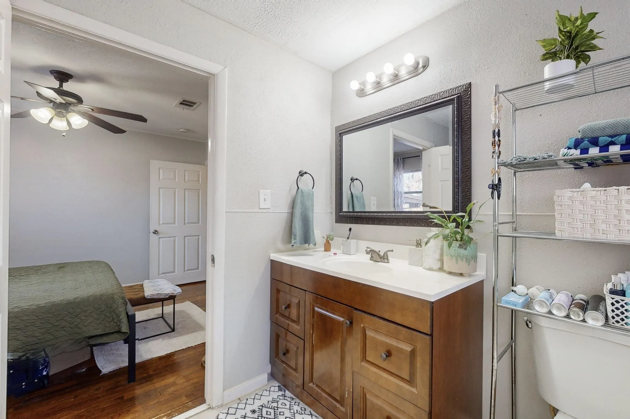Ensuite bathroom with vanity, light wood-style floors, a textured ceiling, and ceiling fan