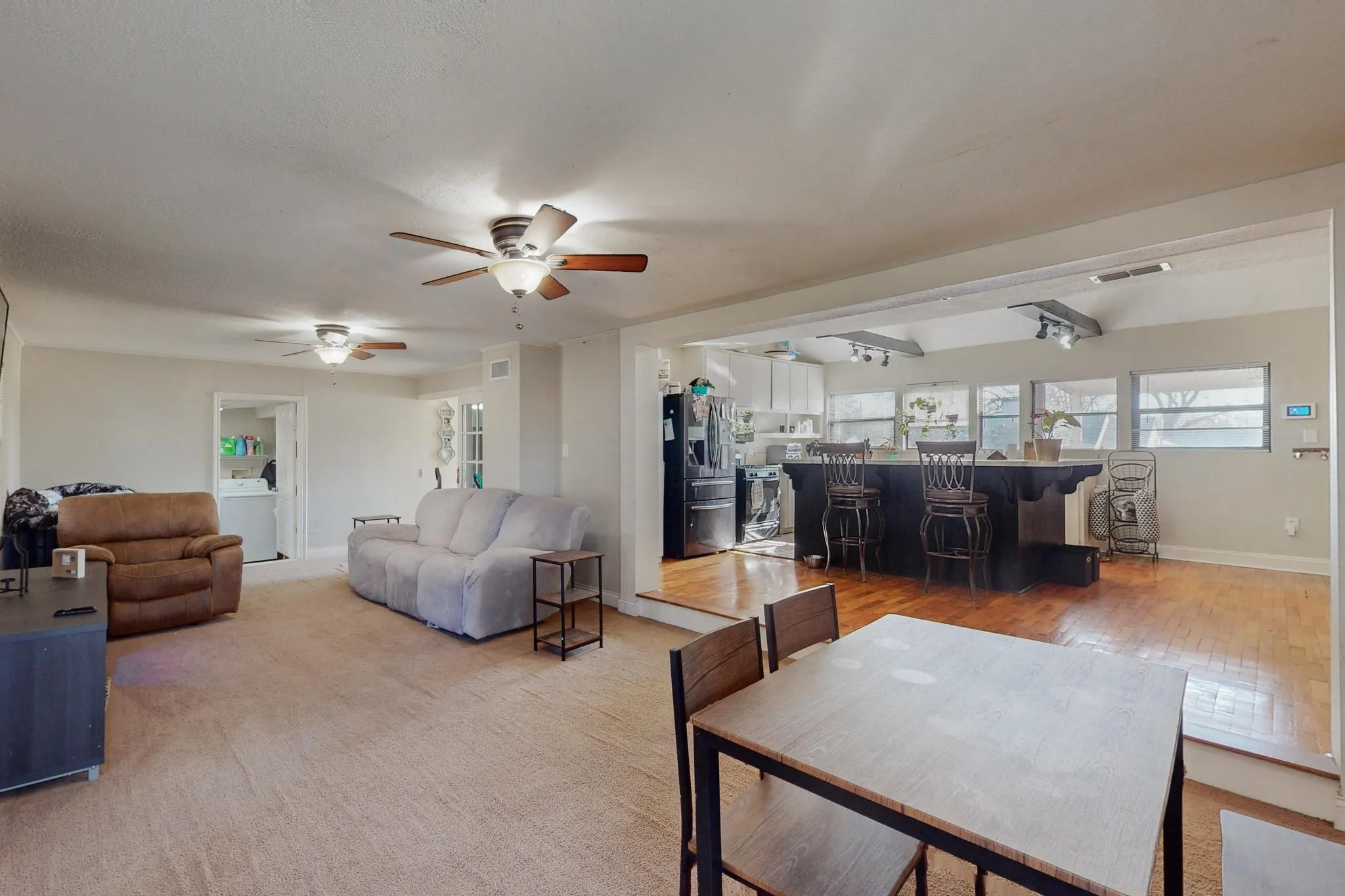 Living room featuring washer / dryer, ceiling fan, and light carpet