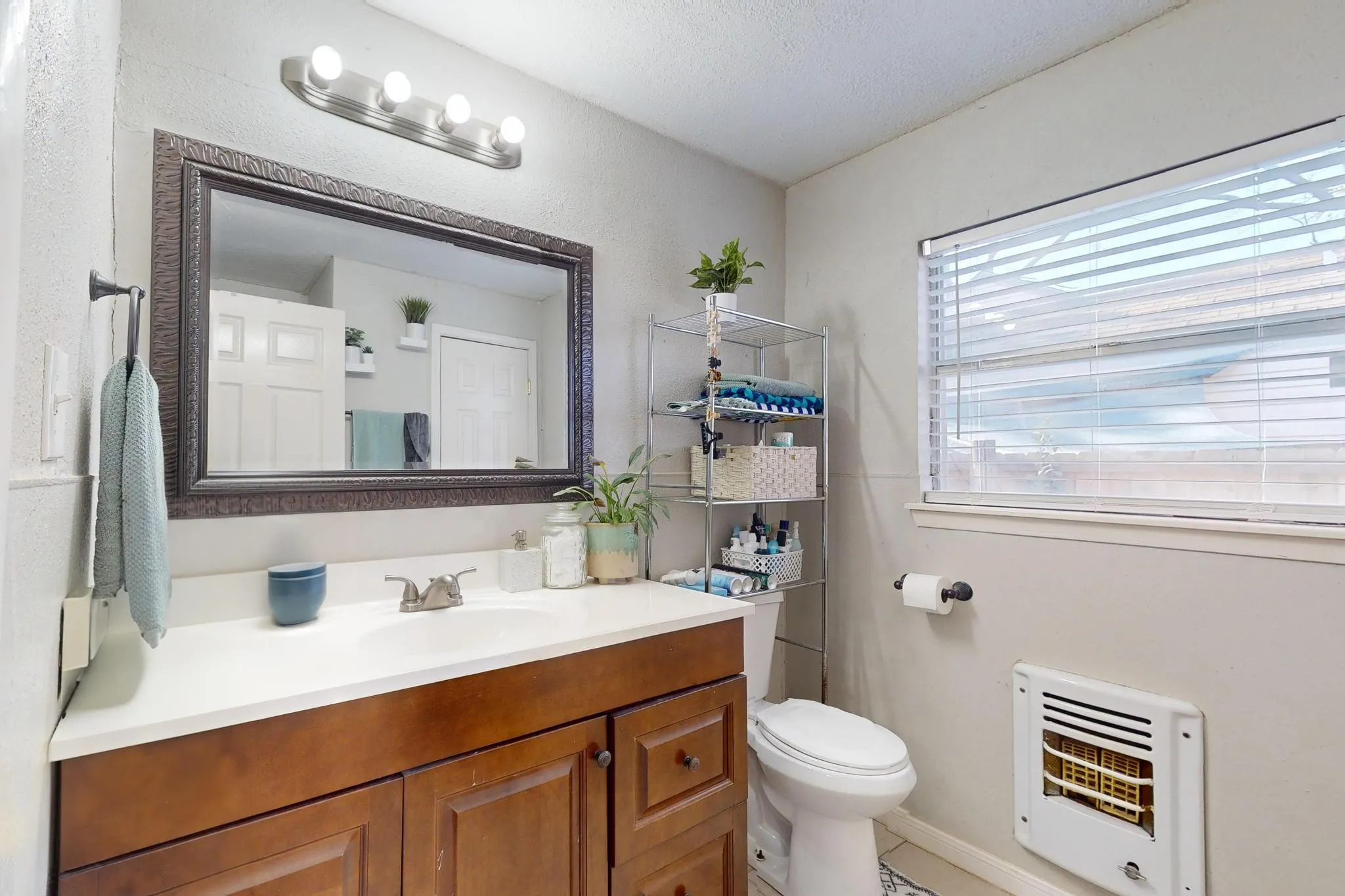 Bathroom with heating unit, vanity, and light tile patterned flooring