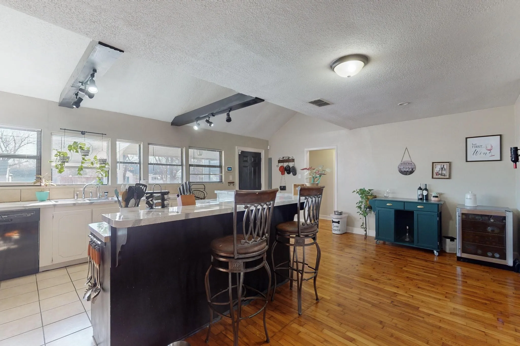 Kitchen with a kitchen breakfast bar, rail lighting, lofted ceiling, light countertops, and dishwasher