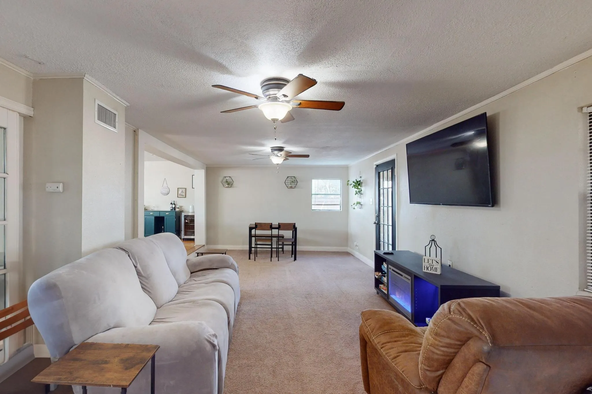Living room featuring carpet, a textured ceiling, a ceiling fan, and ornamental molding