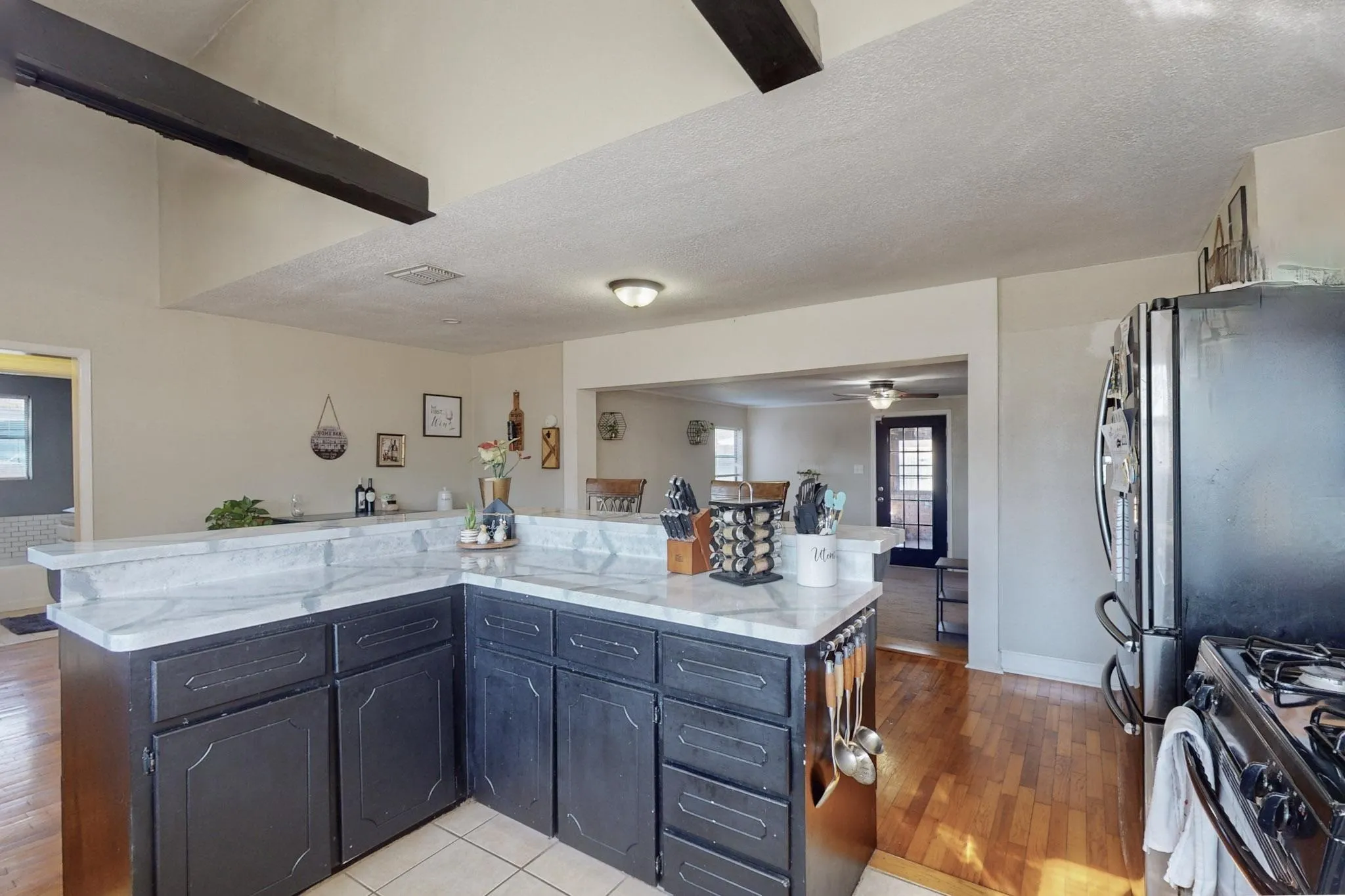 Kitchen with a textured ceiling, a center island, light stone counters, dark cabinetry, and range with gas cooktop