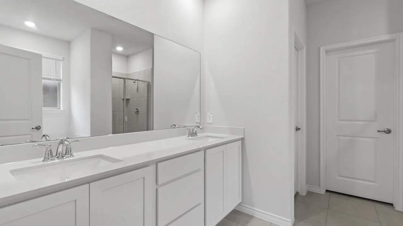 Dual vanity featuring white cabinetry, integrated sinks, chrome fixtures, and a large wall-mounted mirror