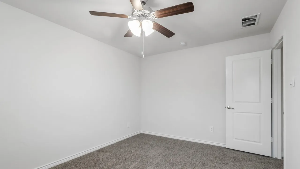 Neutral wall tones with a ceiling fan featuring wood-finish blades and integrated lighting