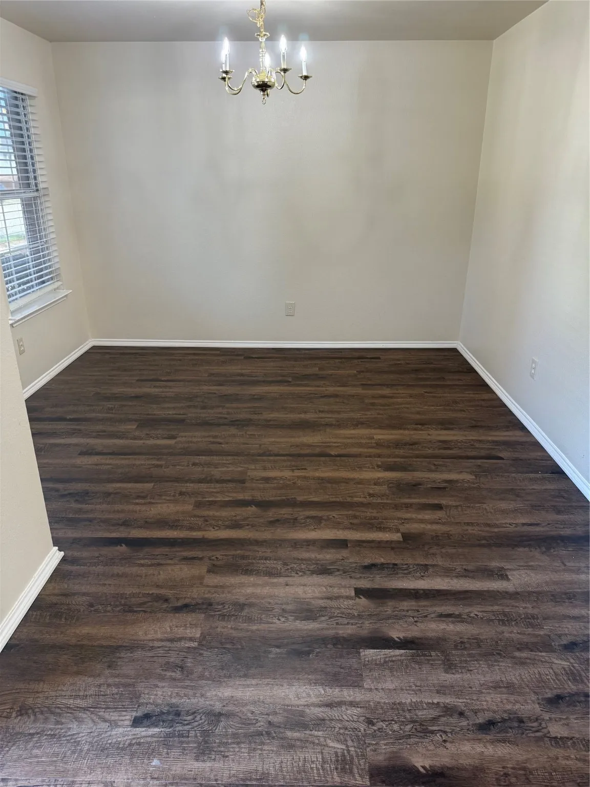 Unfurnished room featuring dark wood finished floors and a chandelier