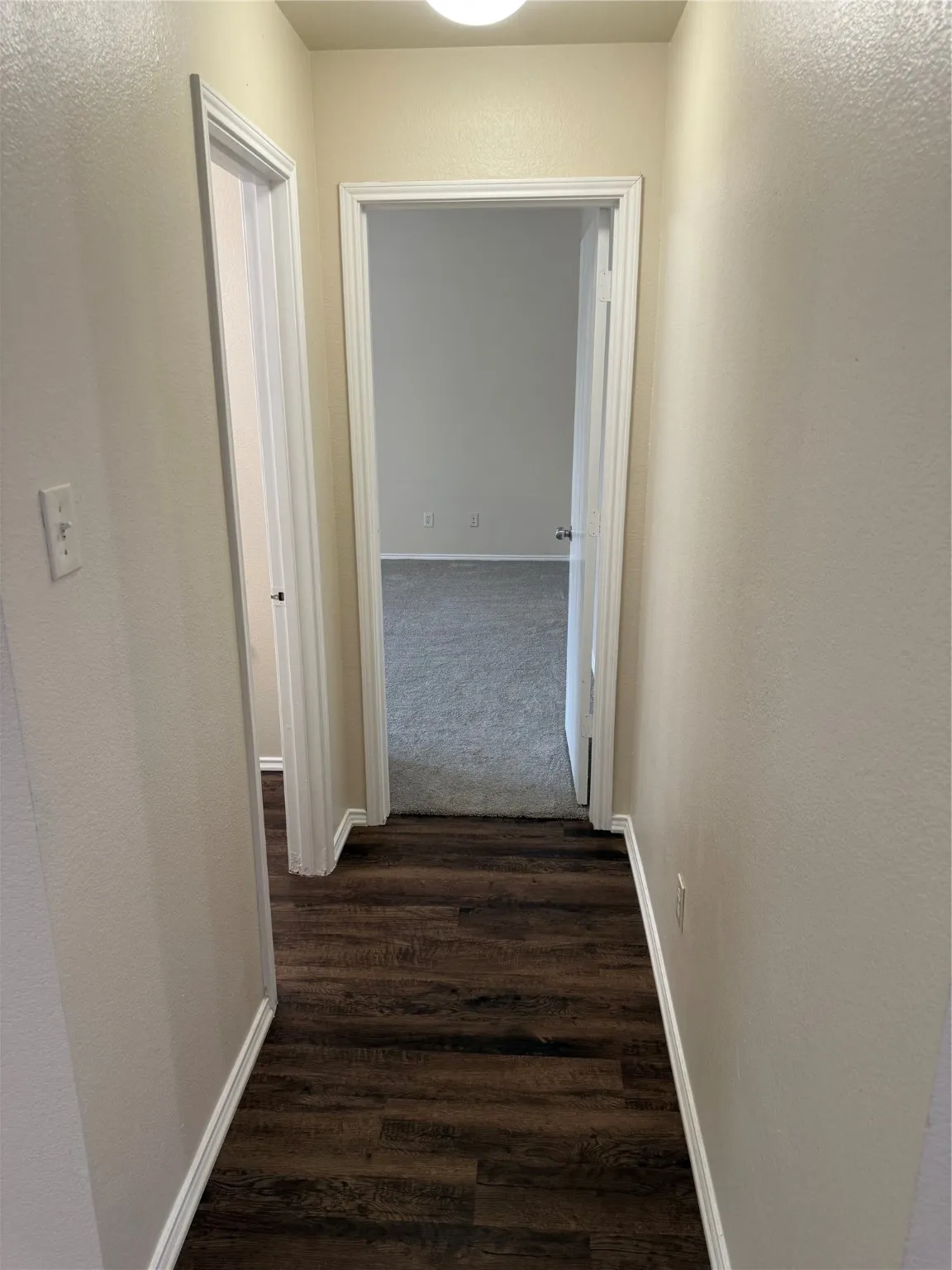 Hallway with a textured wall and dark wood finished floors
