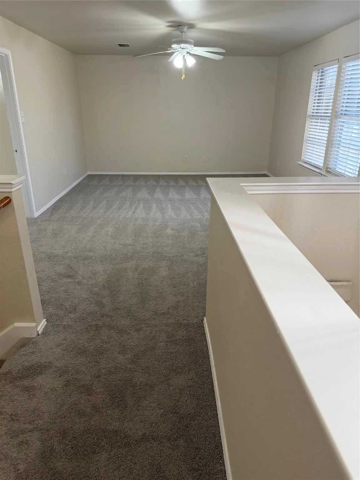 Carpeted empty room featuring baseboards and ceiling fan