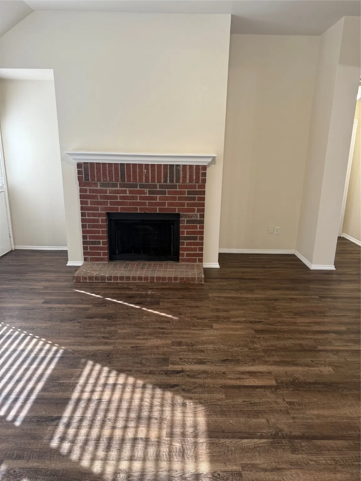 Unfurnished living room with a fireplace and dark wood-type flooring