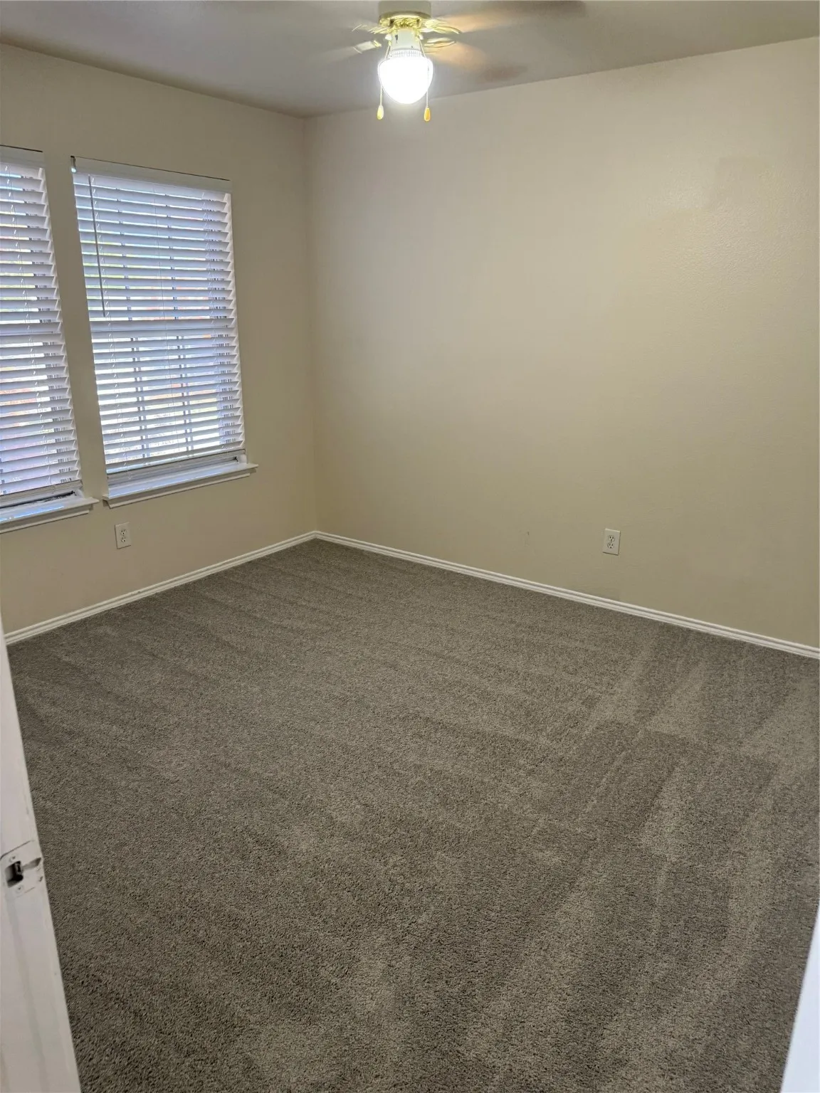 Empty room with carpet flooring and a ceiling fan