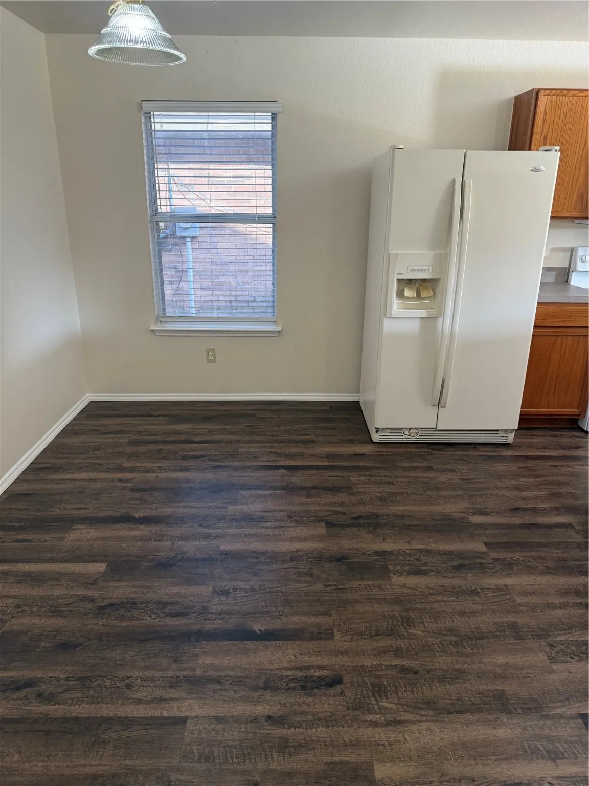 Unfurnished dining area with dark wood-style floors and baseboards