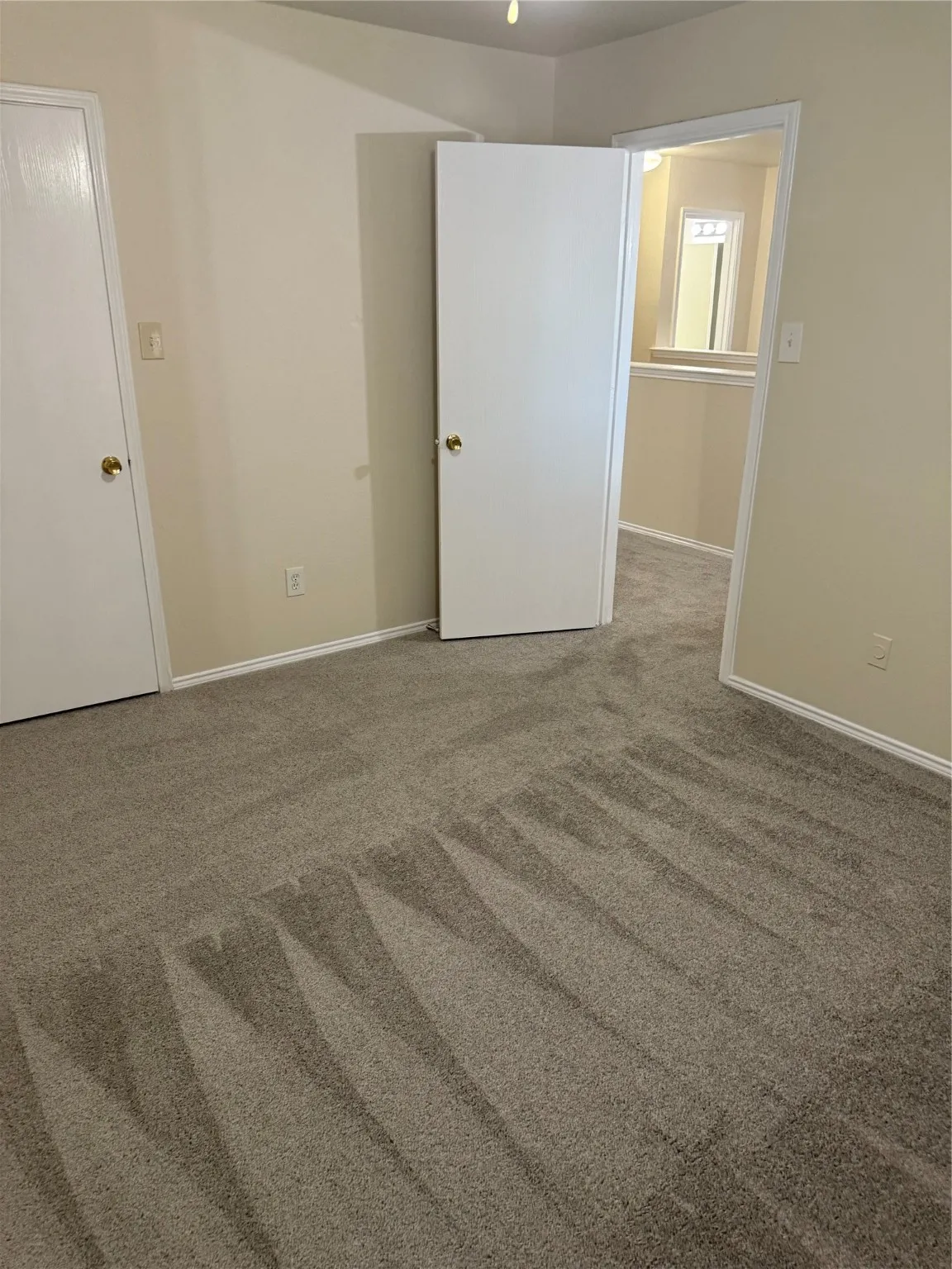 Empty room featuring light colored carpet and baseboards