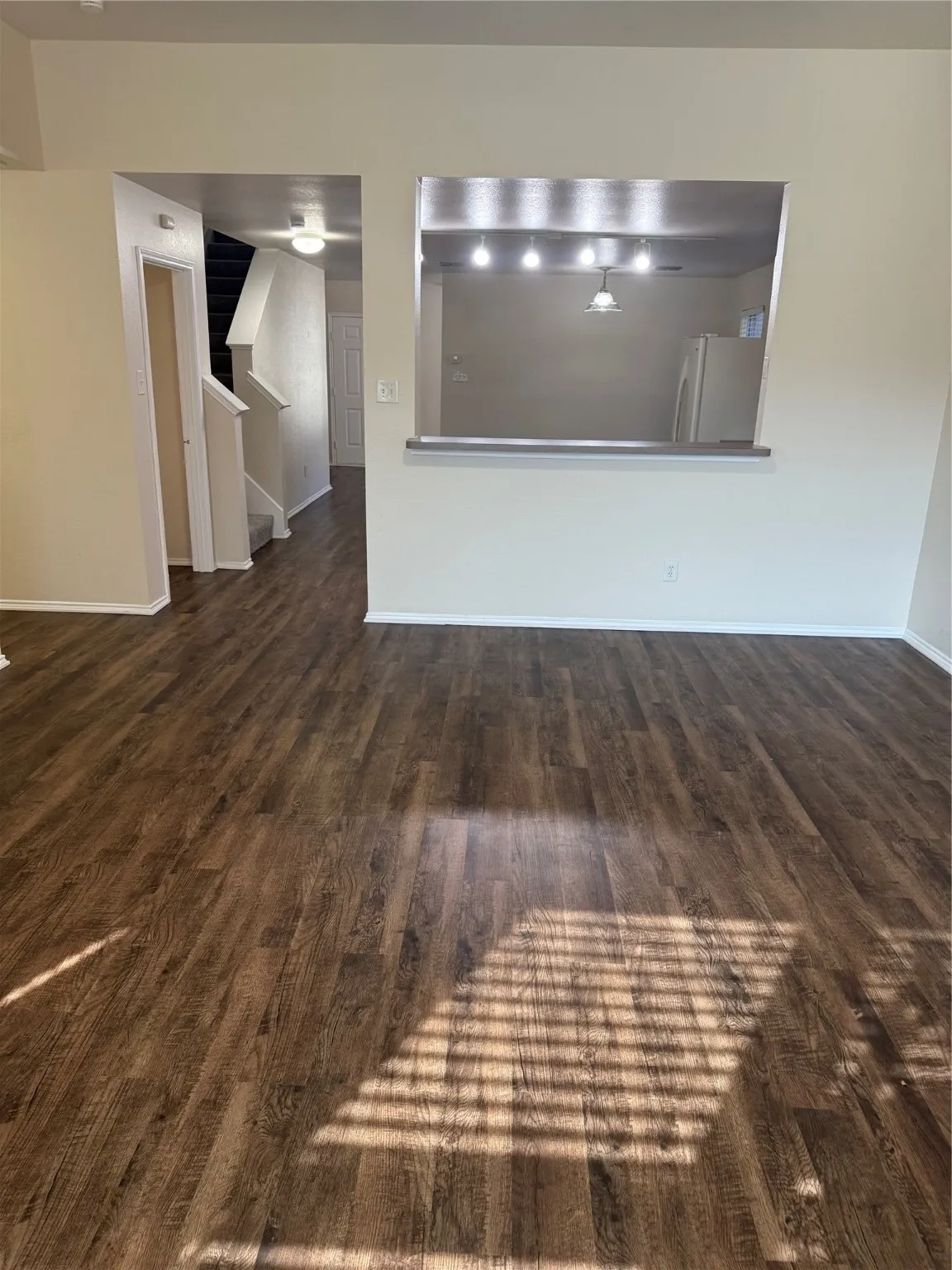 Unfurnished living room featuring dark wood-type flooring and stairs