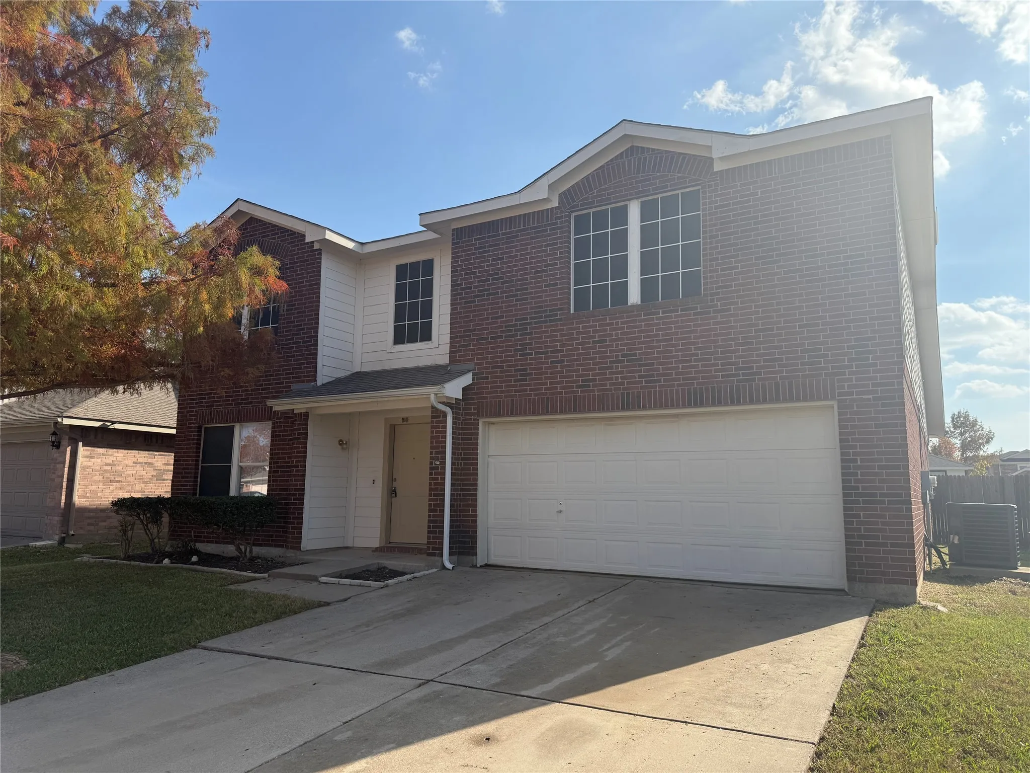 Traditional-style home featuring brick siding, an attached garage, driveway, and a front yard