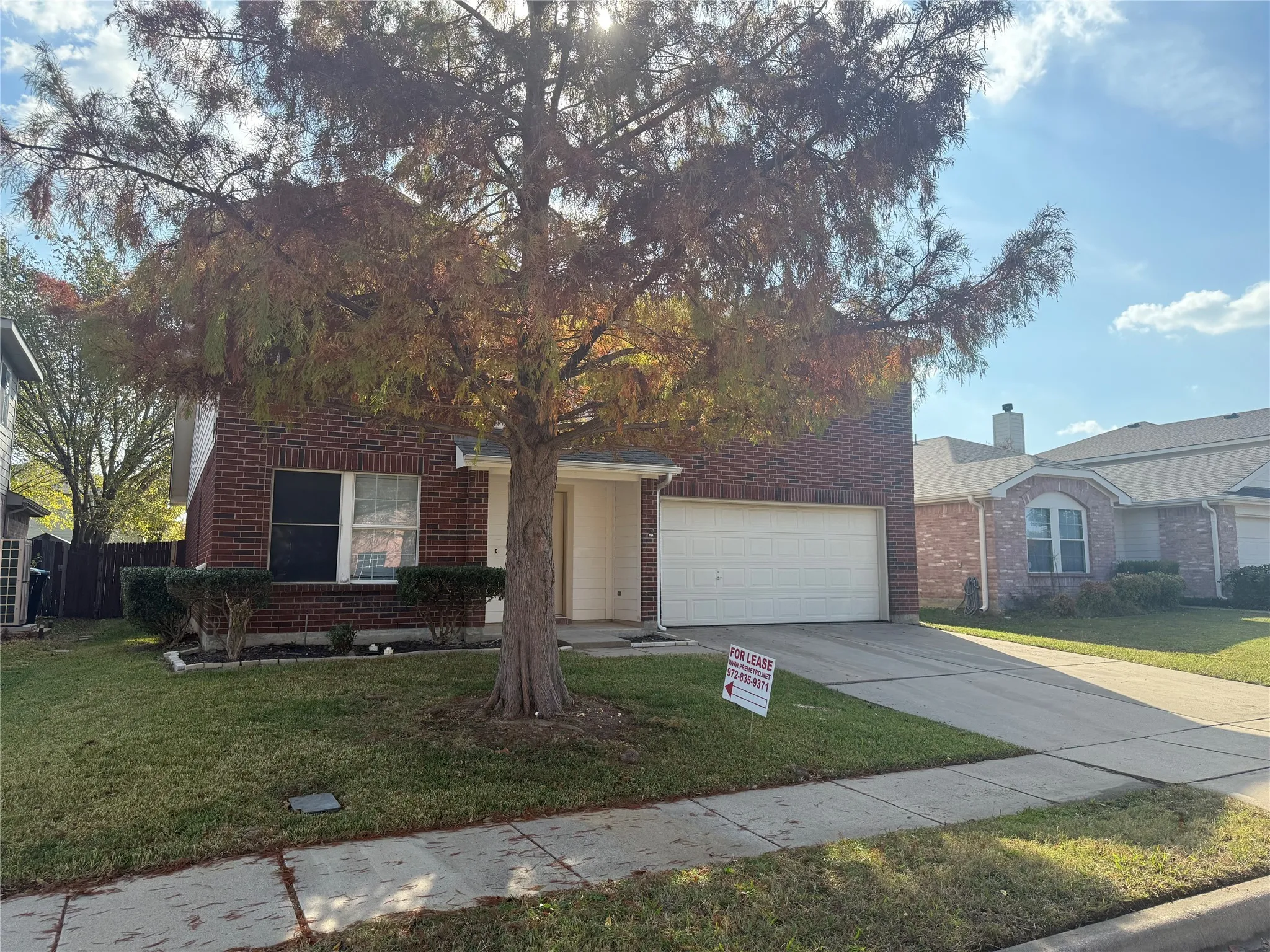 Obstructed view of property featuring brick siding, a front lawn, and driveway