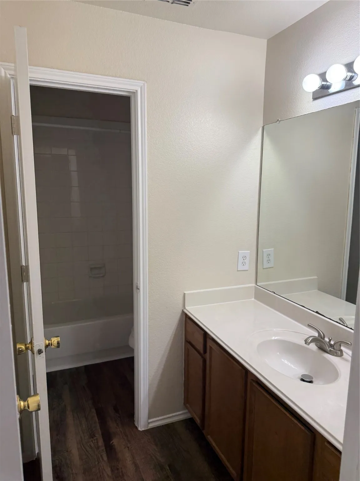 Bathroom featuring vanity, dark wood-style floors, and shower / tub combination