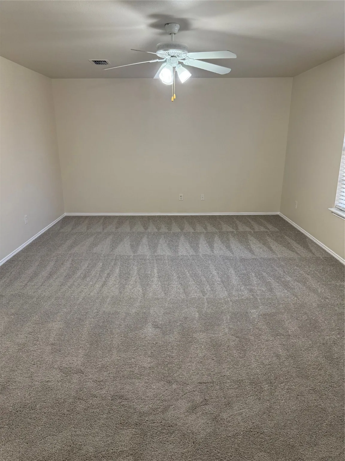 Empty room with light colored carpet and baseboards