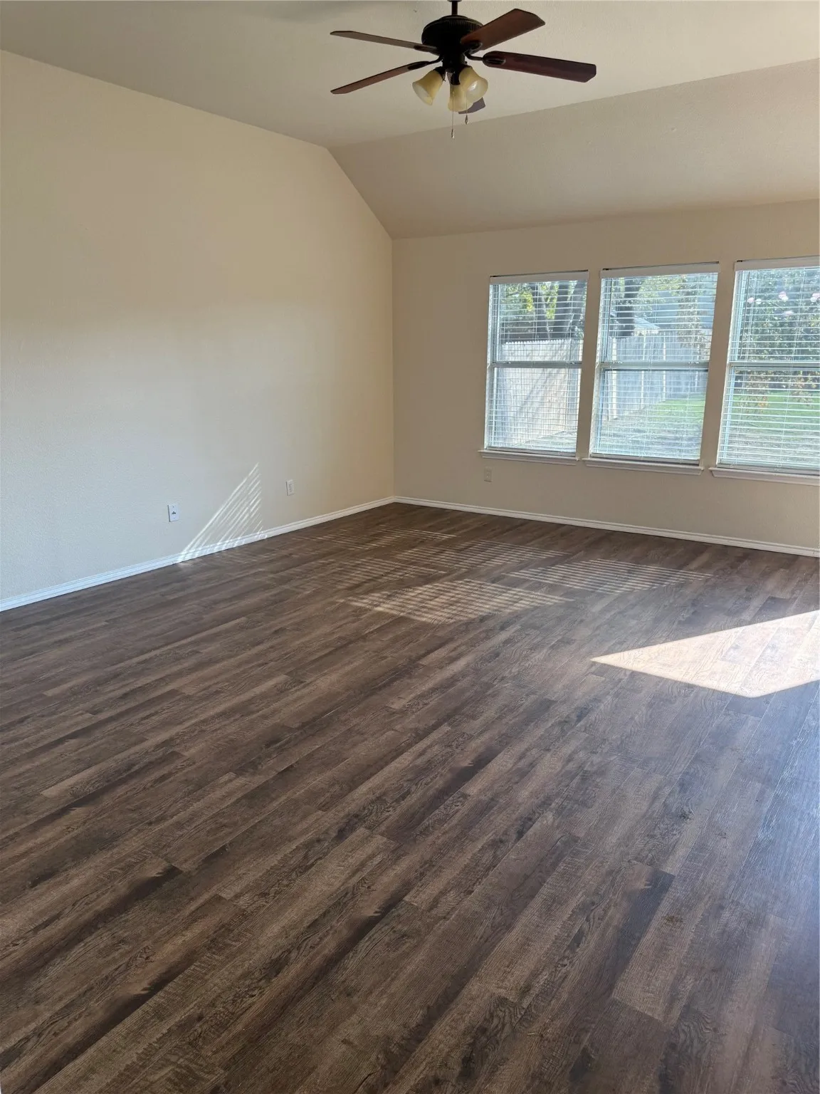 Spare room with lofted ceiling, dark wood finished floors, and ceiling fan