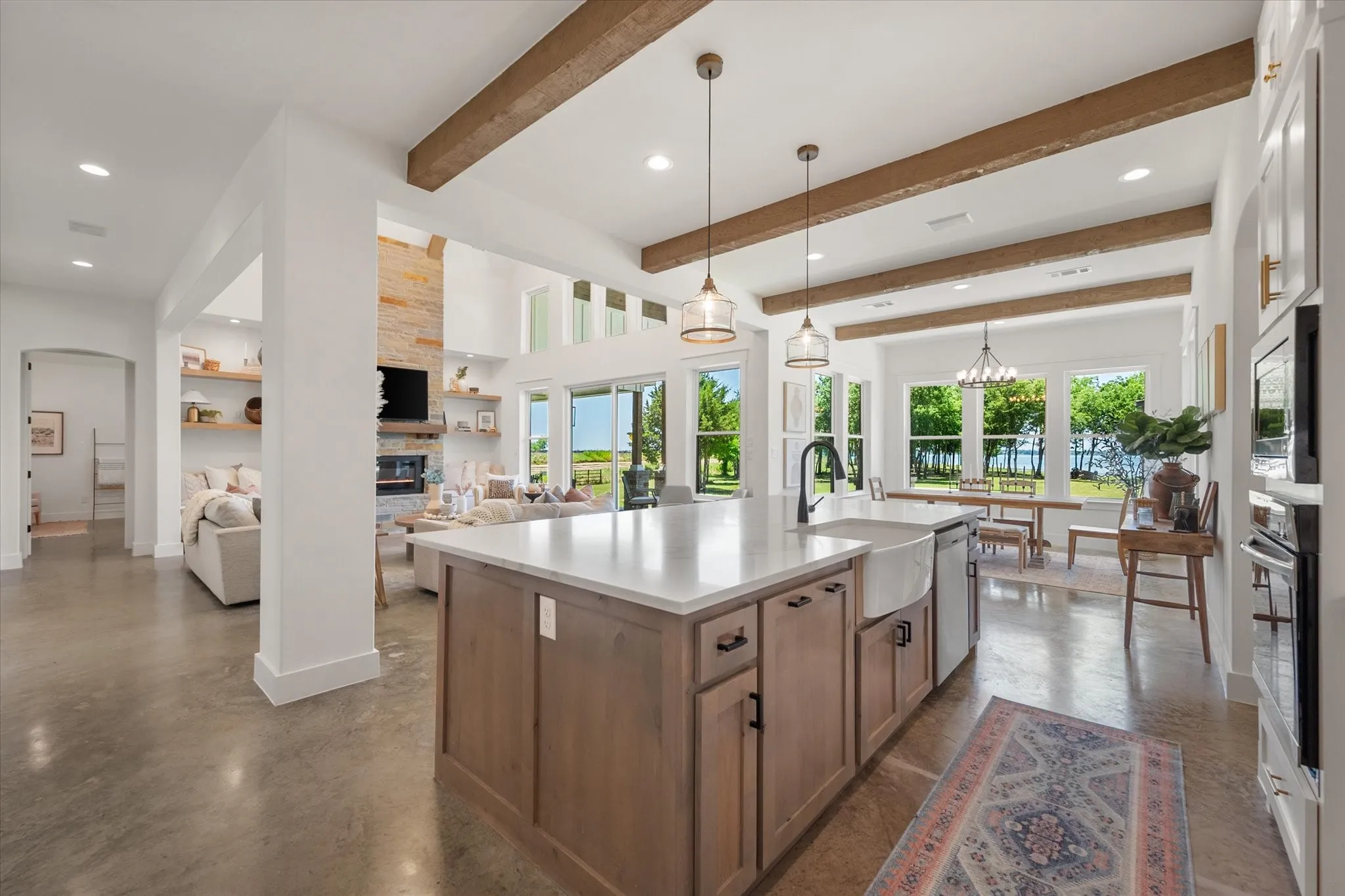 Kitchen featuring a fireplace, recessed lighting, open floor plan, an island with sink, and decorative light fixtures