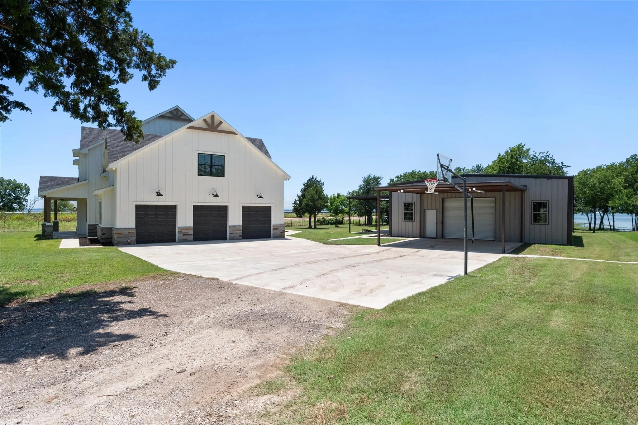 View of property exterior with a yard, stone siding, a detached garage, driveway, and board and batten siding