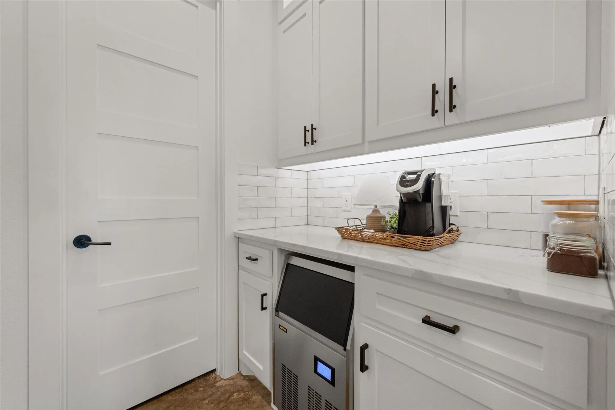 Bar area featuring light stone counters, white cabinets, and tasteful backsplash