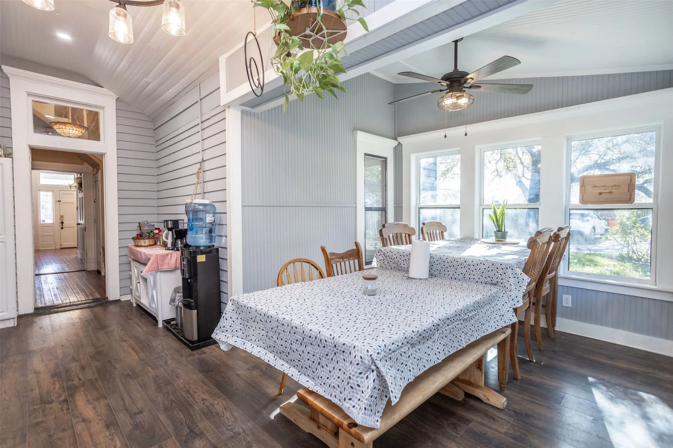 Dining space with lofted ceiling, dark wood finished floors, a ceiling fan, and wood walls