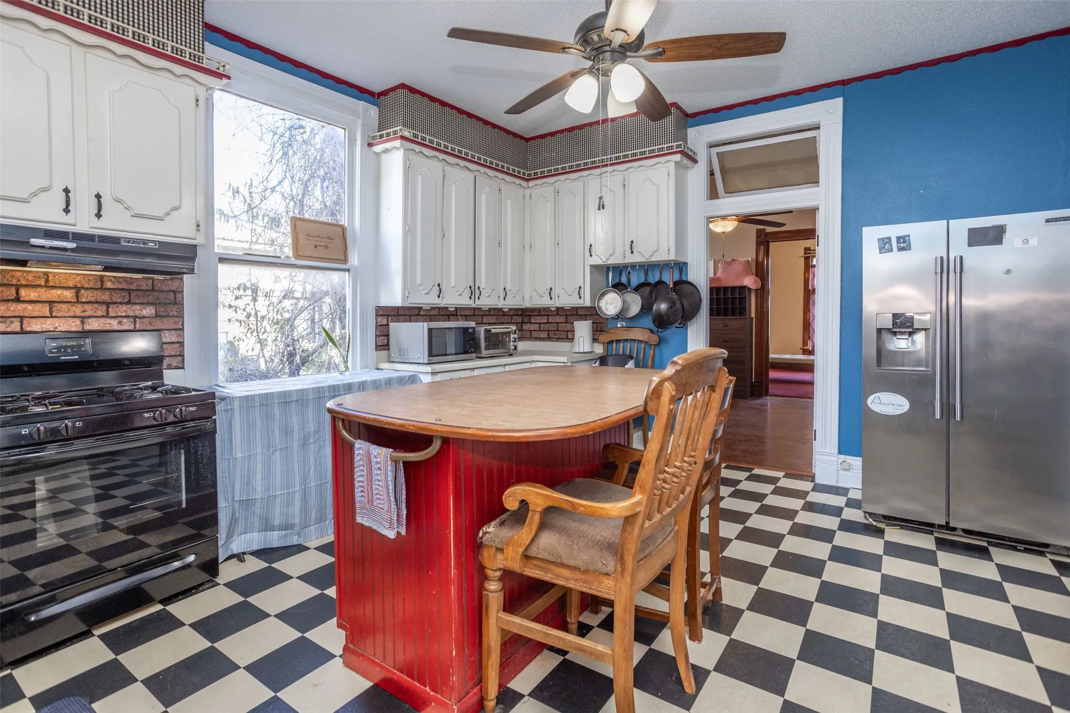 Kitchen with dark floors, light countertops, a kitchen breakfast bar, appliances with stainless steel finishes, and crown molding