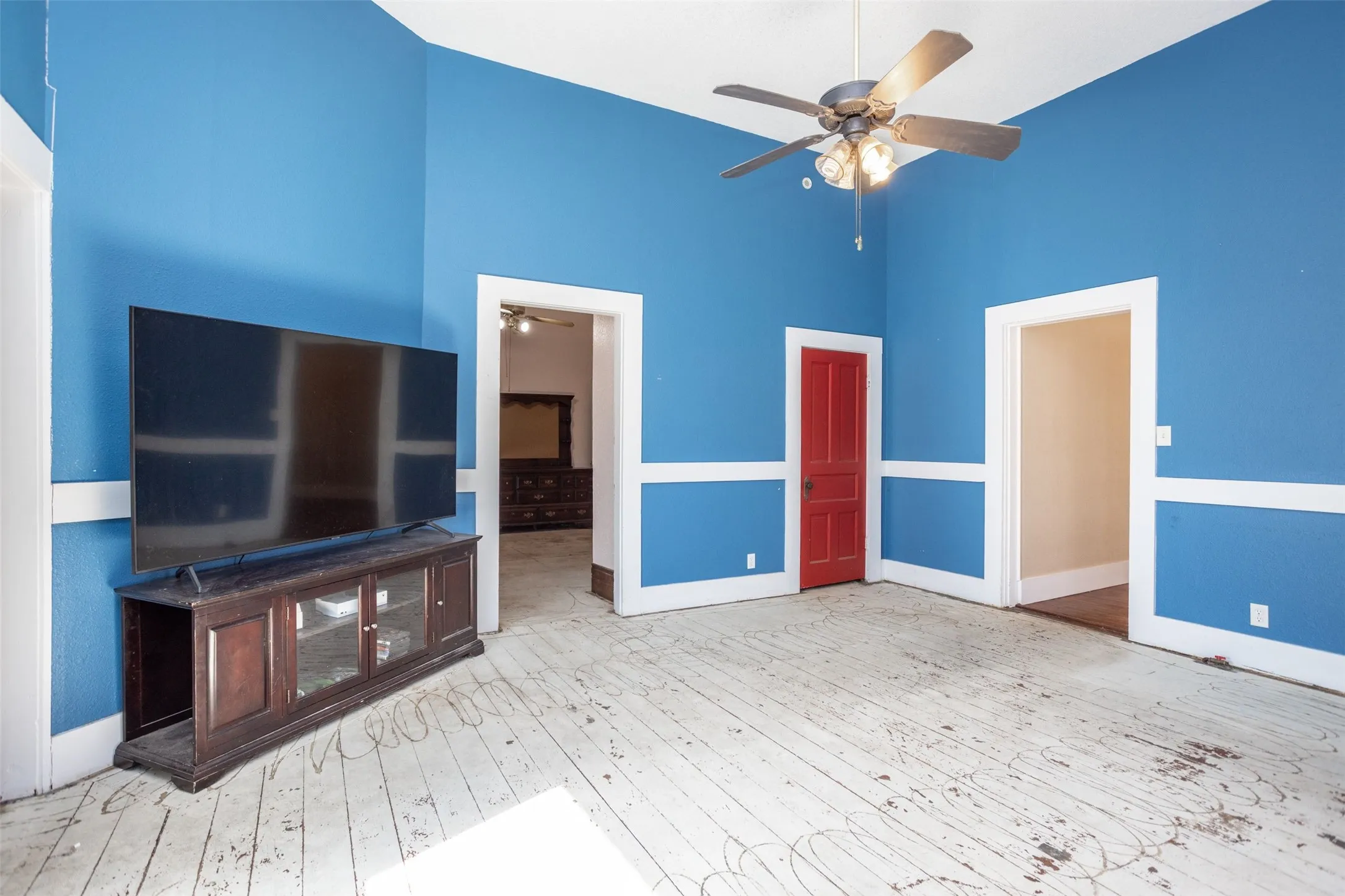 living room with light wood-style flooring, a high ceiling, and a ceiling fan
