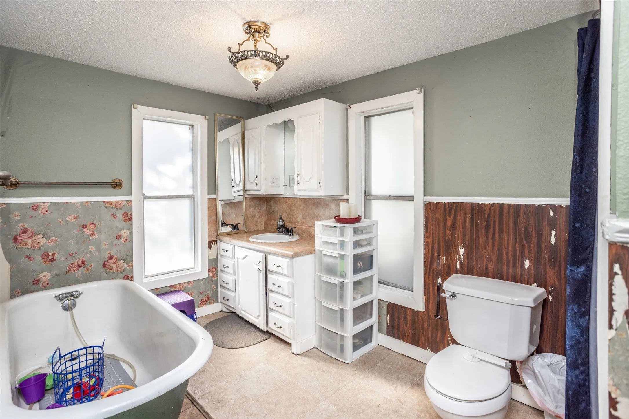 Full bath featuring wainscoting, vanity, a freestanding bath, a textured ceiling, and wooden walls
