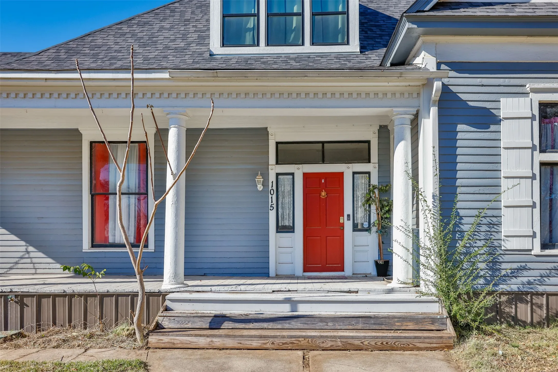 Doorway to property with a porch and a shingled roof