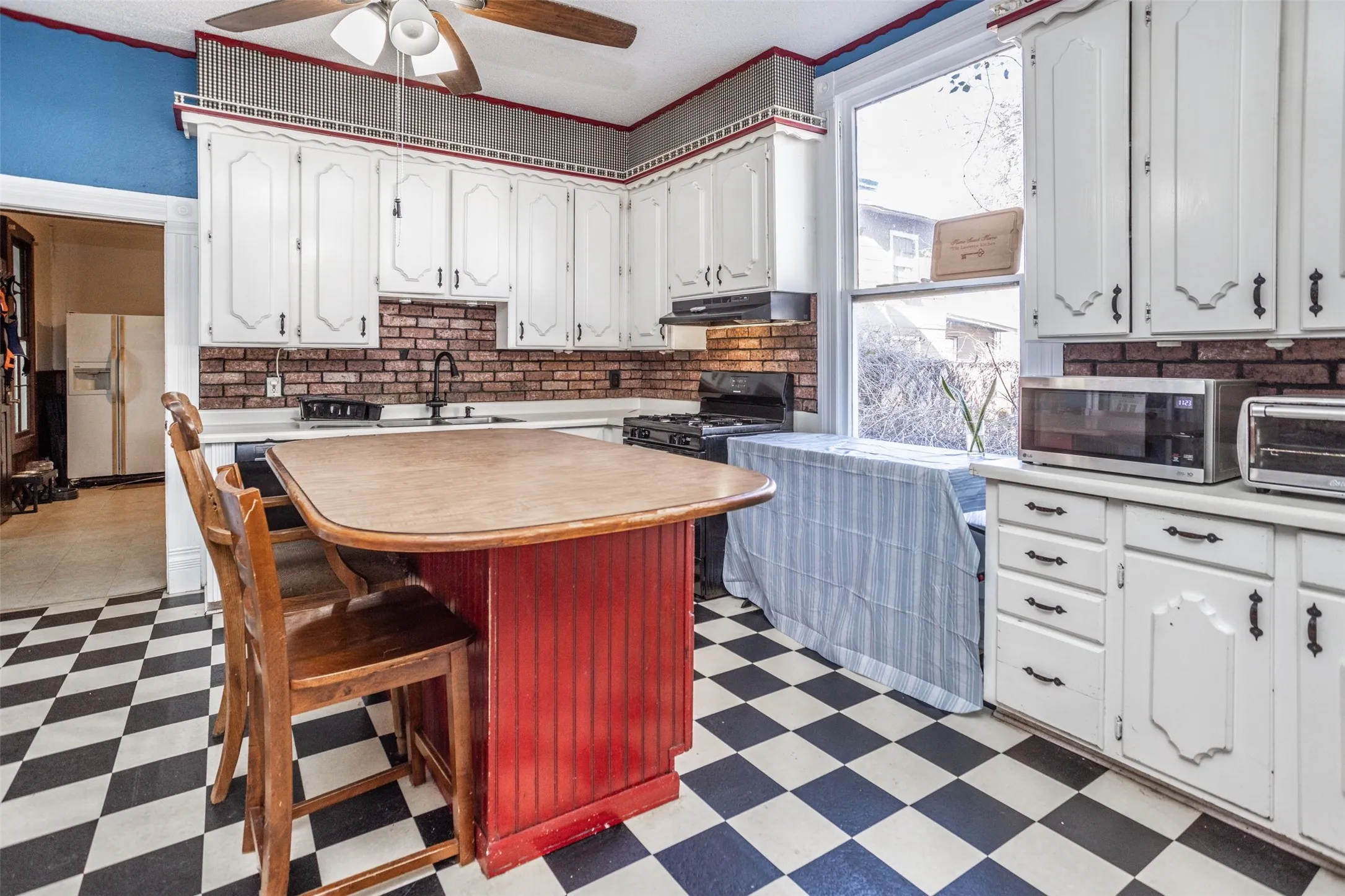 Kitchen with dark flooring, light countertops, a kitchen island, white cabinetry, and crown molding