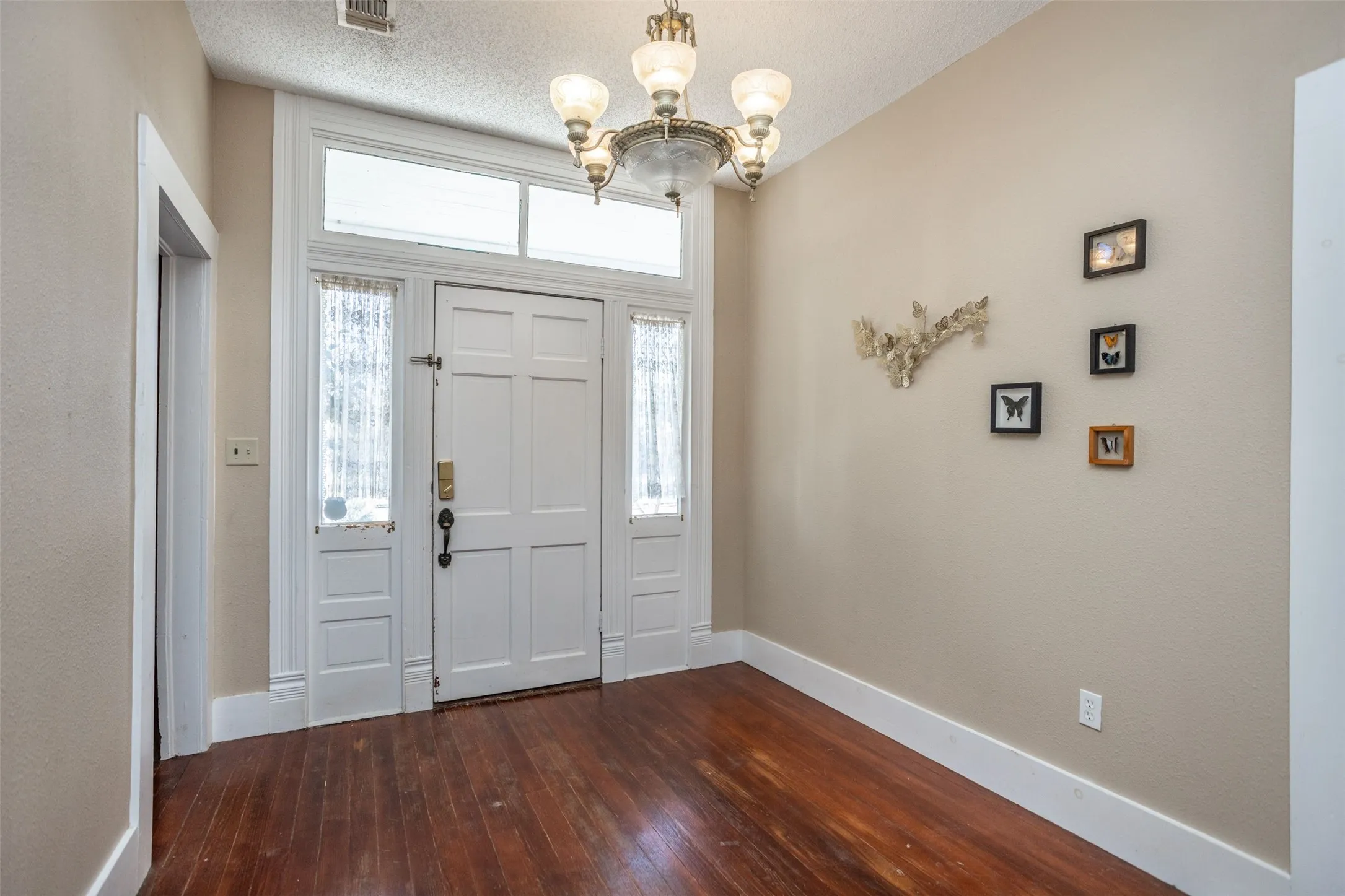 Entryway with dark wood-style flooring, a chandelier, and a textured ceiling