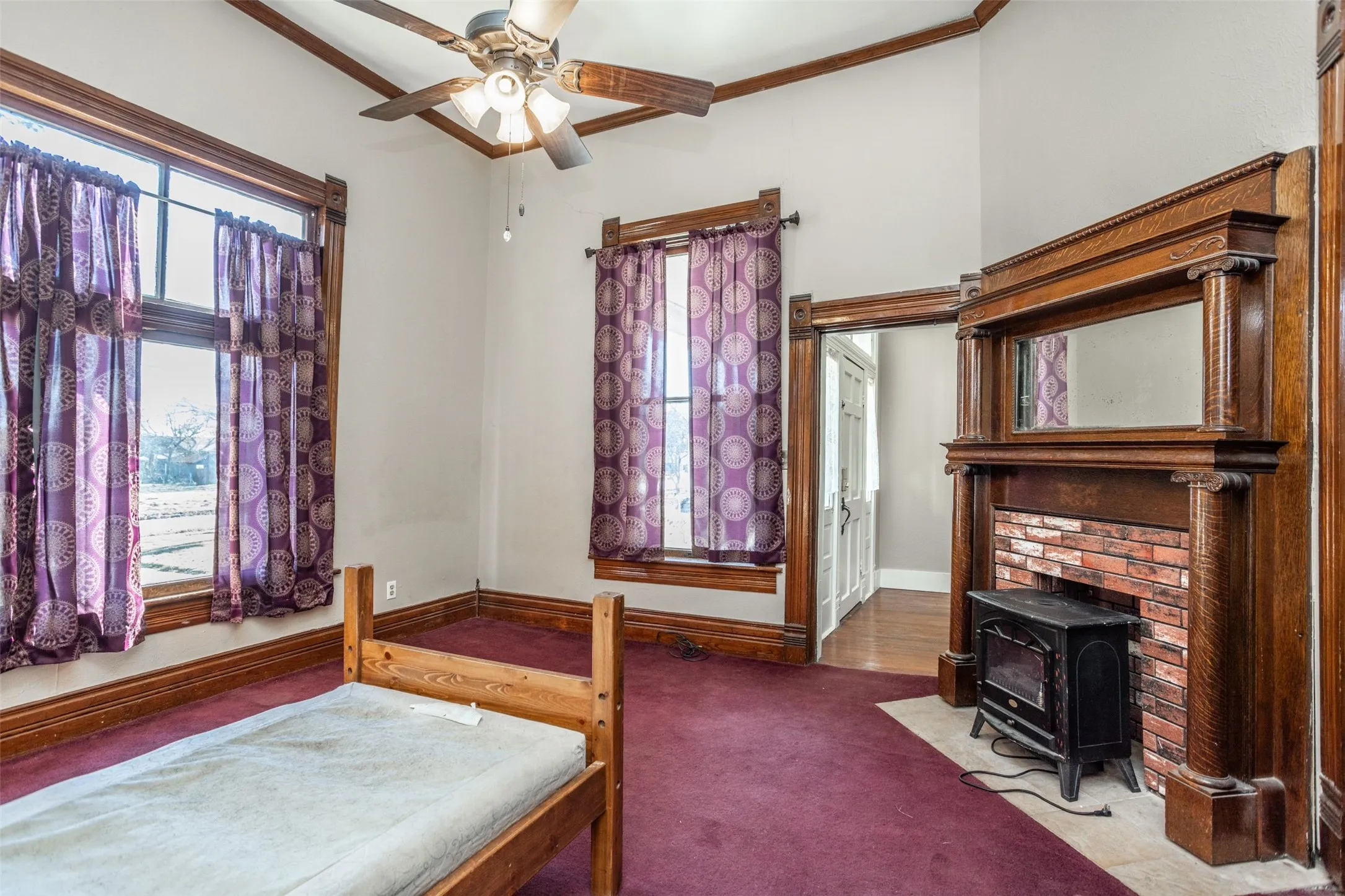 Carpeted bedroom with a decorative fireplace, ceiling fan, and ornamental molding