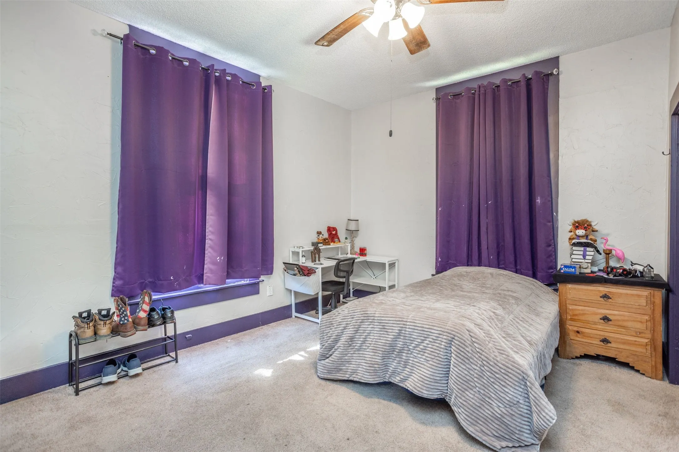 Carpeted bedroom featuring ceiling fan and a textured ceiling
