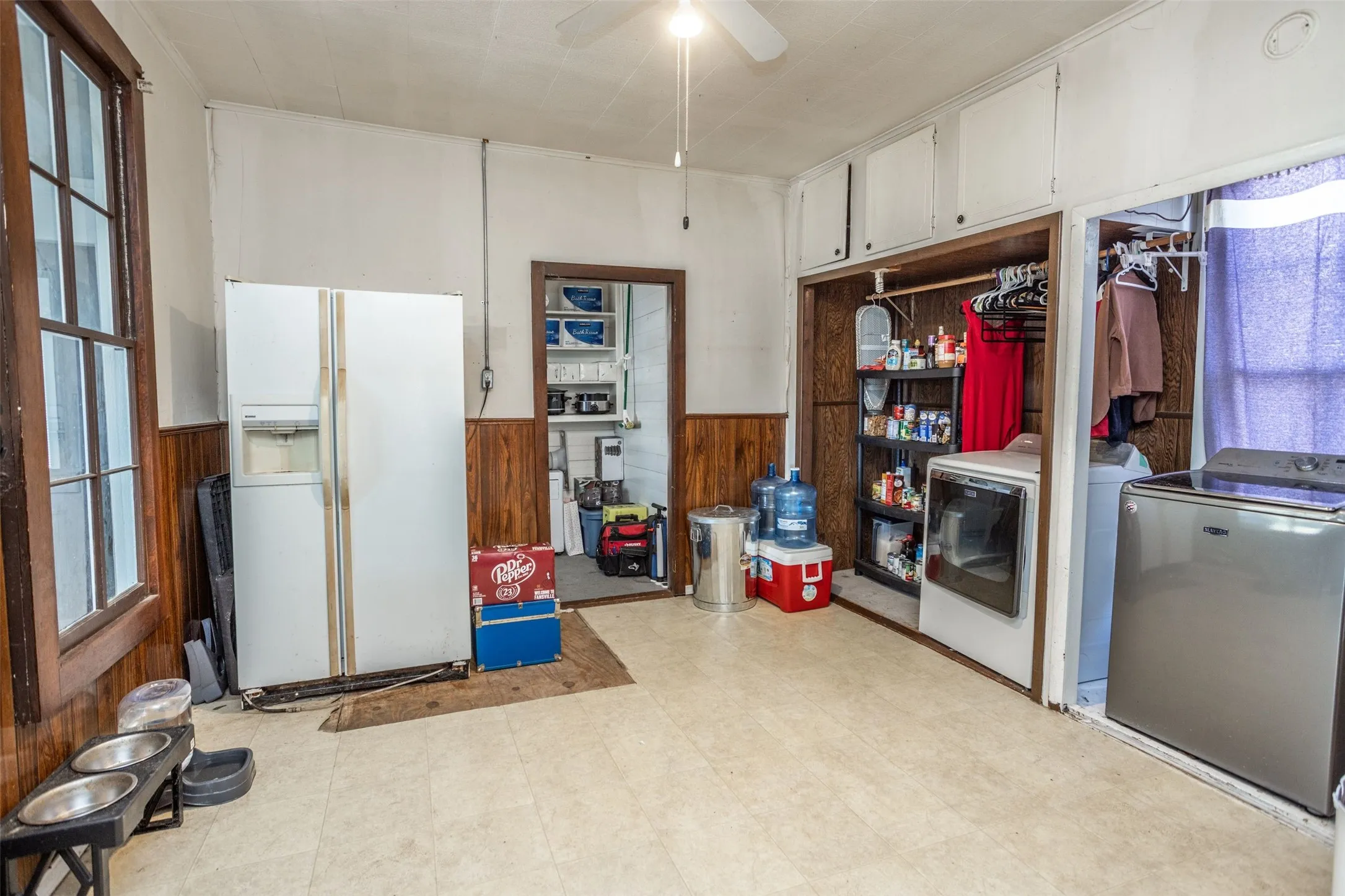 Mudroom/Laundry roomwith light floors, wainscoting, white fridge with ice dispenser, wooden walls, and washer and clothes dryer