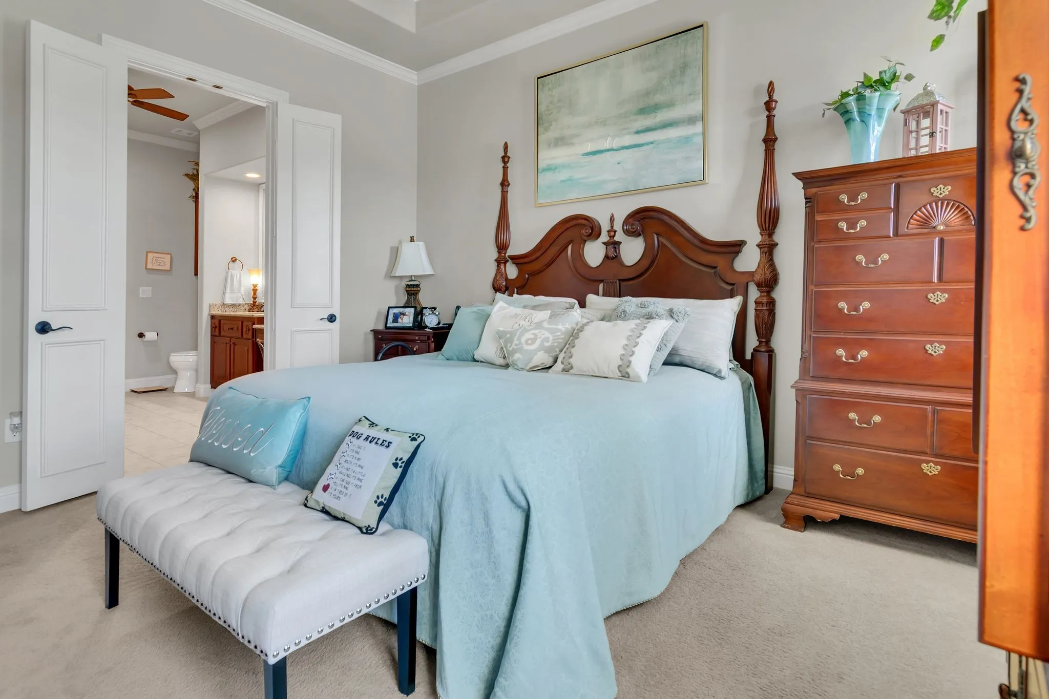 Bedroom featuring ornamental molding, light carpet, and ensuite bath