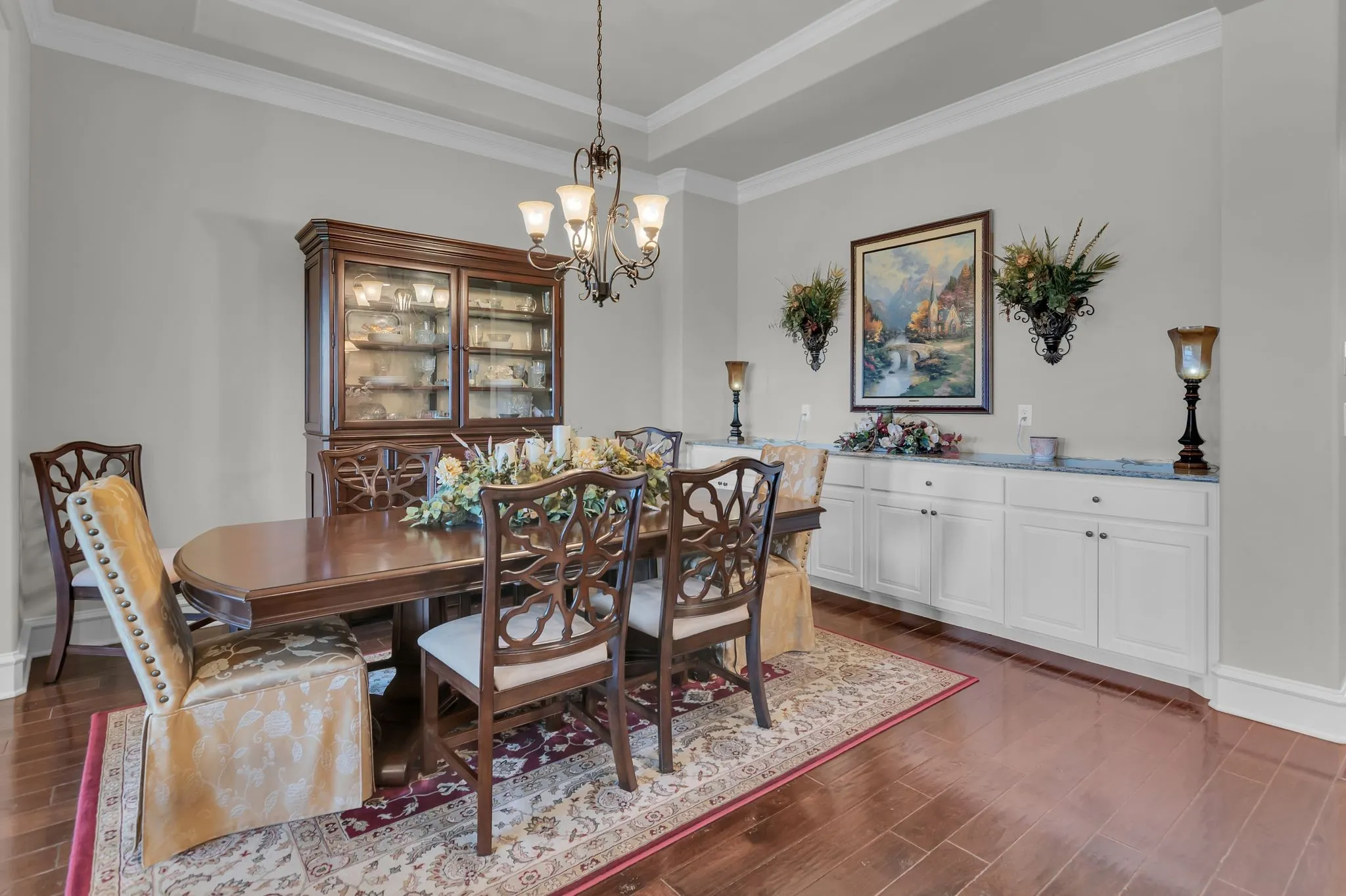 Dining room featuring wood finish floors, a chandelier, ornamental molding, and a raised ceiling