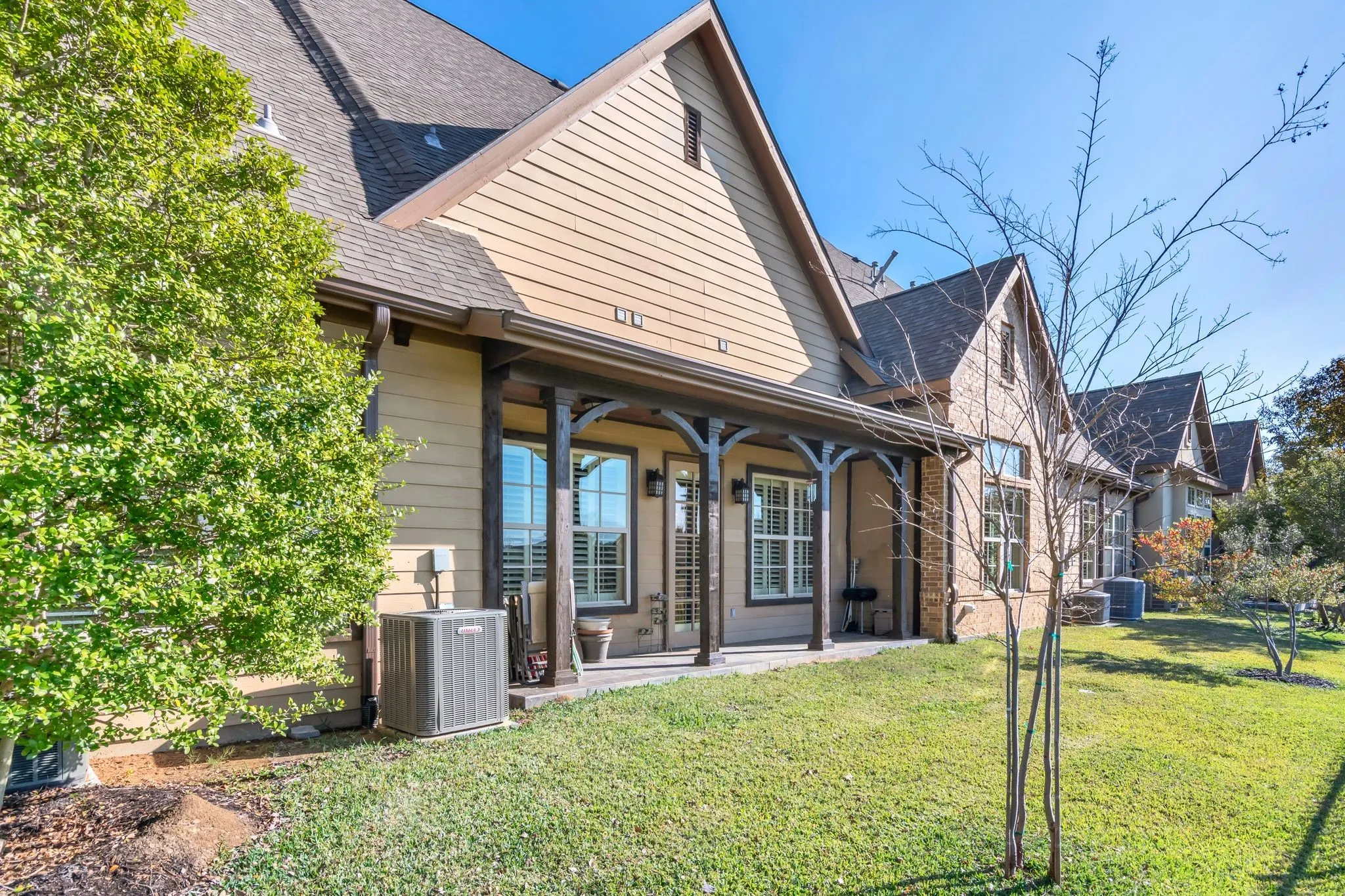 Back of house featuring a shingled roof, a lawn, and a patio area