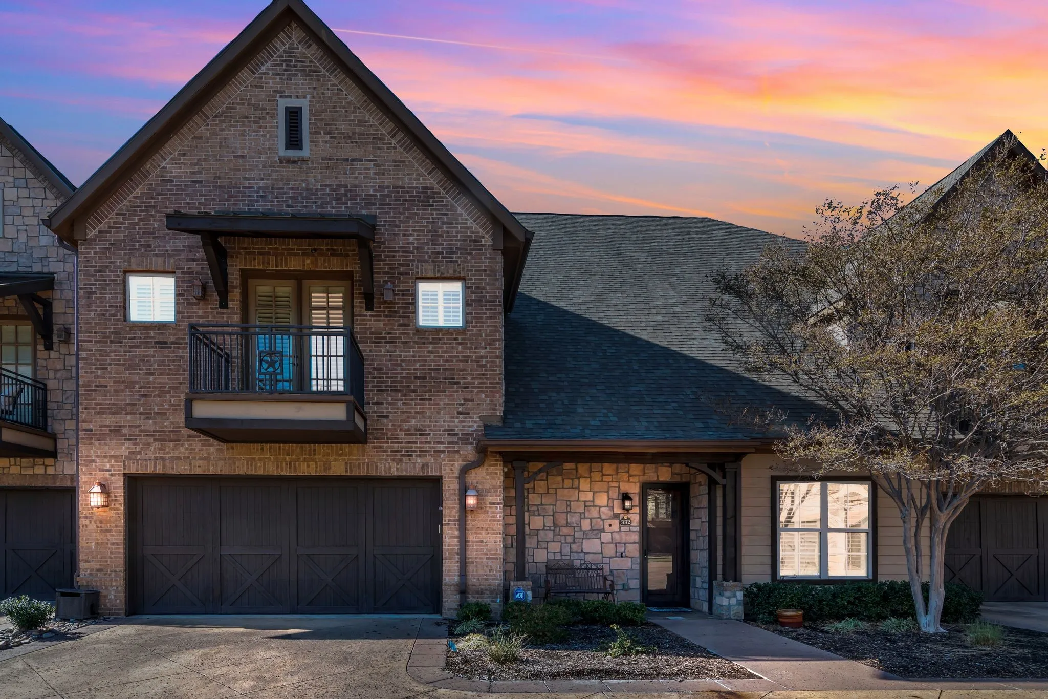 View of front facade with a balcony, concrete driveway, a shingled roof, an attached garage, and brick siding