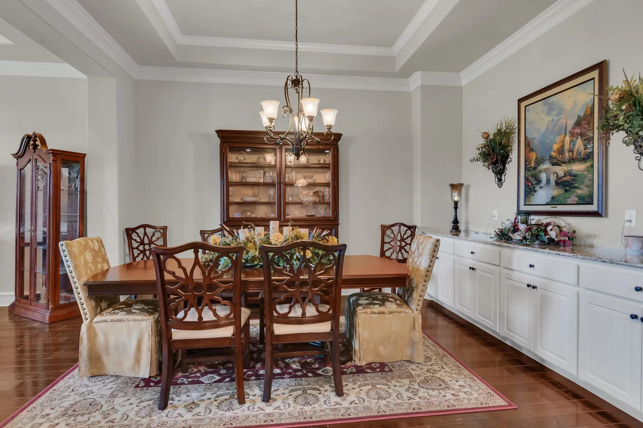 Dining area with a chandelier, dark wood floors, ornamental molding, and a raised ceiling