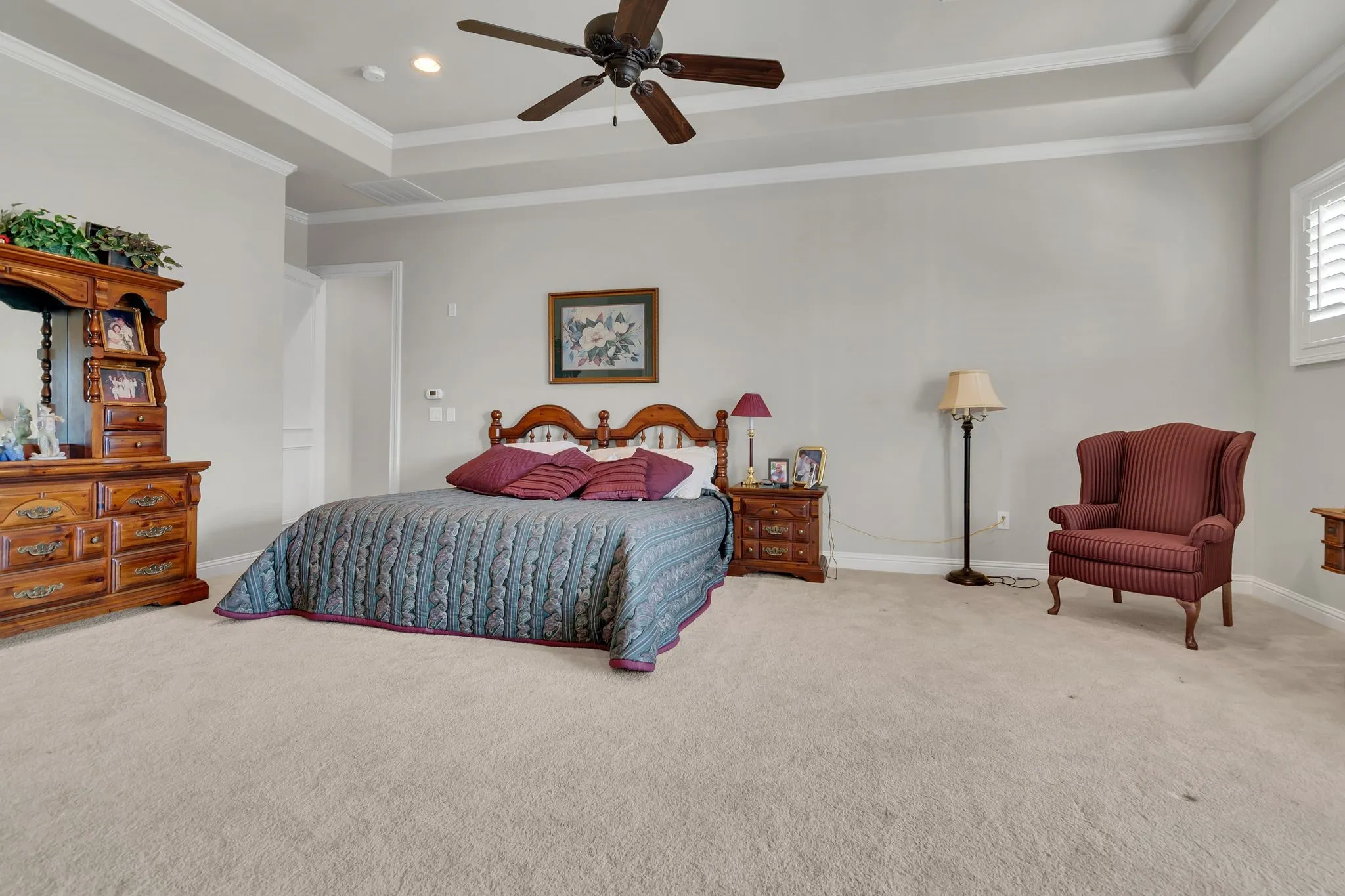 Bonus room with full bath, closet and balcony, featuring ornamental molding, light colored carpet, a ceiling fan, and raised ceiling.  Can be used as game room or 3rd bedroom.