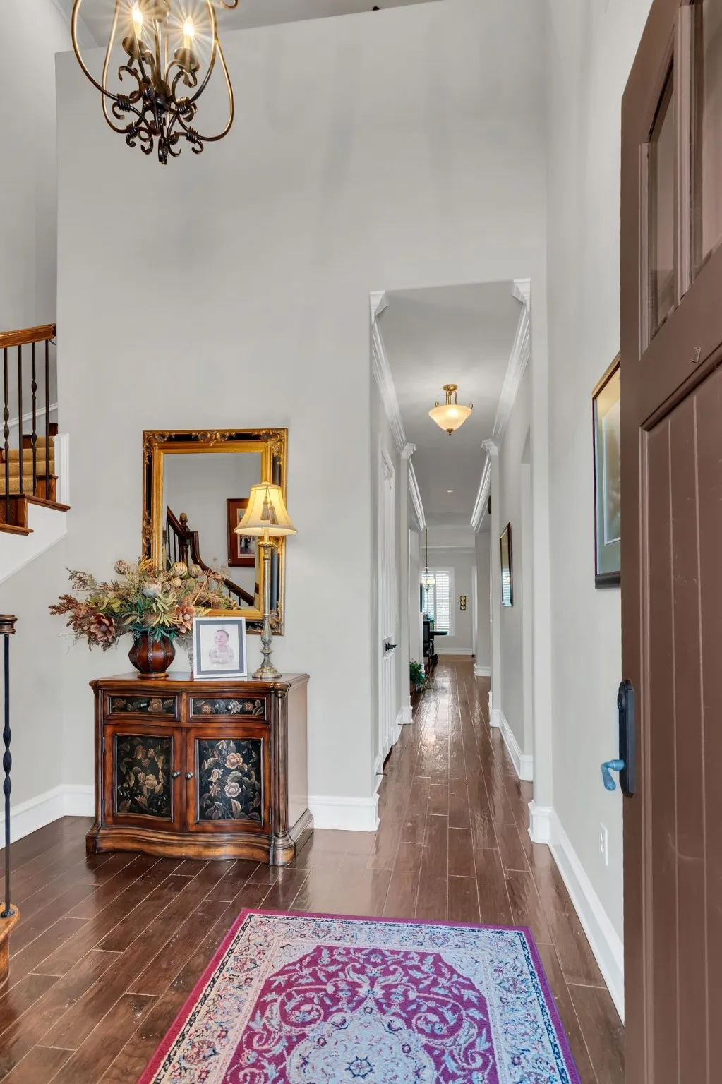 Corridor featuring ornamental molding, wood floors, and a chandelier